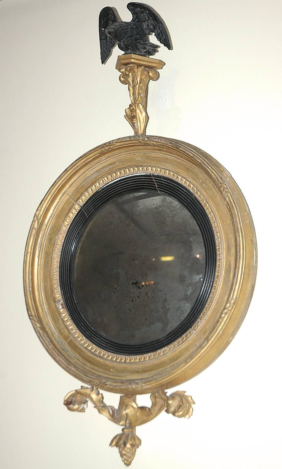 18th century American, Federal girandole mirror with carved and ebonized eagle above round giltwood frame with convex glass and ending in carved acanthus leaves and pine cone.

Dimensions: 19" wide x 33 1/4" high.