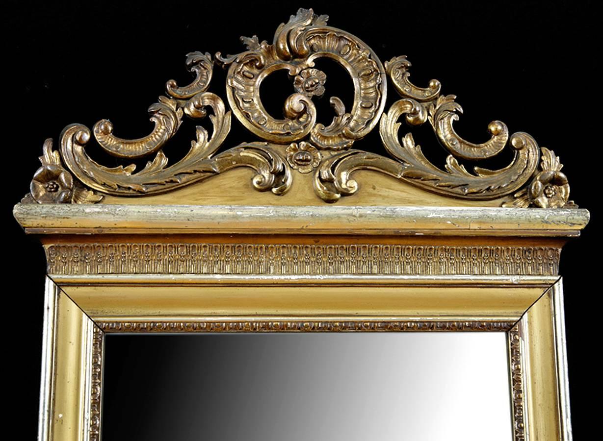 A beautiful accent mirror with carved wood & gesso frame with gold & silver leaf. Finish shows wear with distress; no attempt has been made to alter the patina of age since it is charming as it is. France, circa 1860. 
A perfect piece in a small