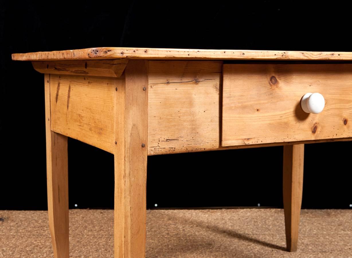 A rectangular pine table with mortise joint, pegged construction and offering one large storage drawer, Northern Germany, circa early 1800s. 
Perfect as a kitchen work table
Note: Should it be needed, we can adapt this to a coffee table and/or paint