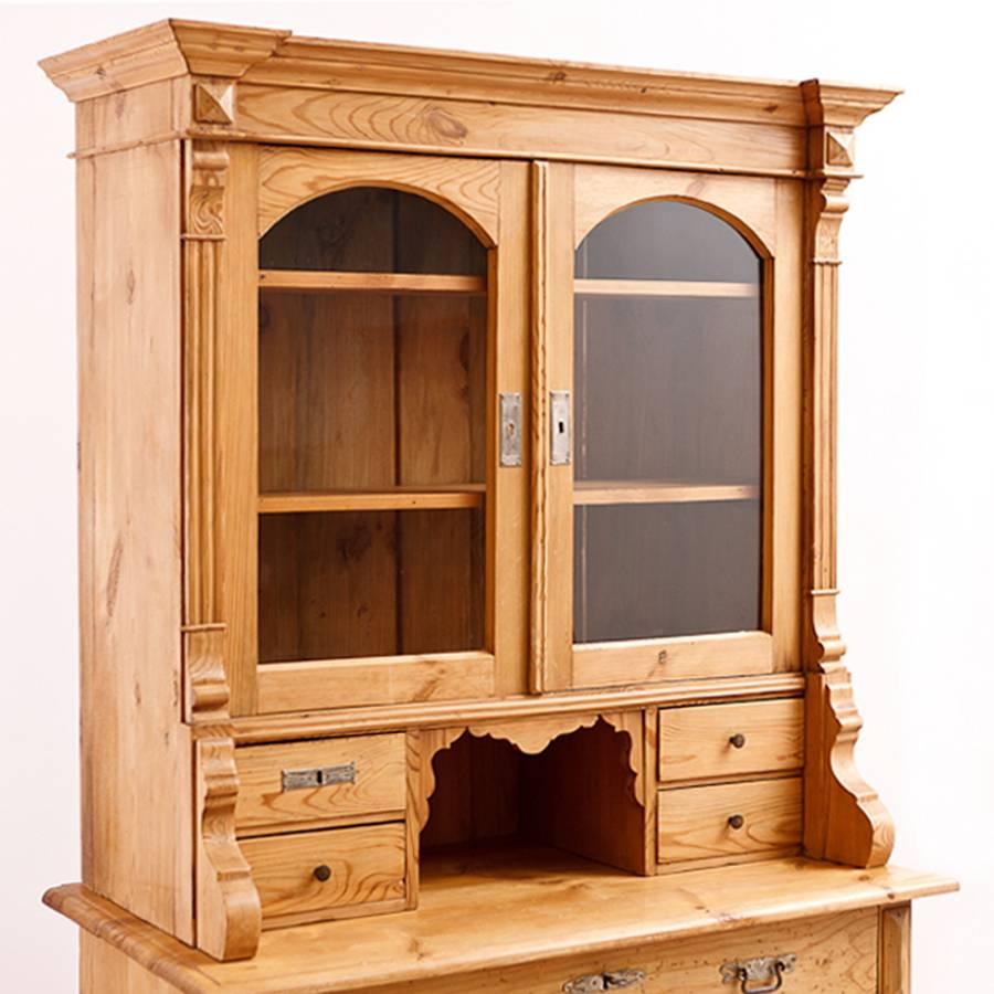 A Gründerzeit Hutch transitioning to Jugendstil in pine with arched glass panels on upper cabinet resting on a chest with four storage drawers. Offers four small drawers flanking an open compartment between top and base, original pulls and