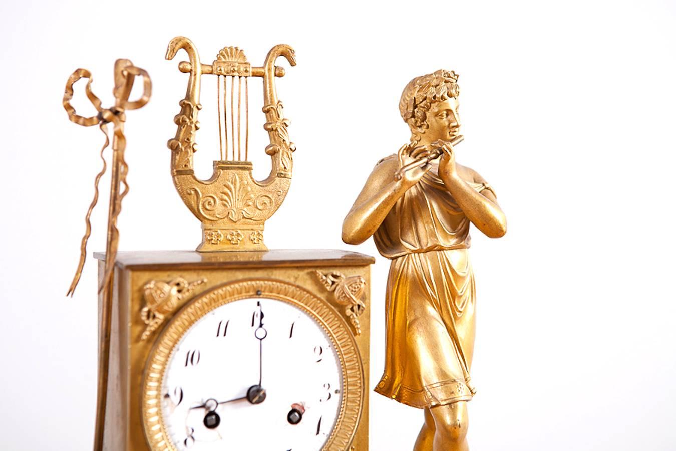 Features a Greek mythological figure playing the flute with a golden lyre and his staff mounted on the time piece, a juxtaposition which serves to counterbalance this exquisite composition. The gilded ormolu is extremely fine as is the overall