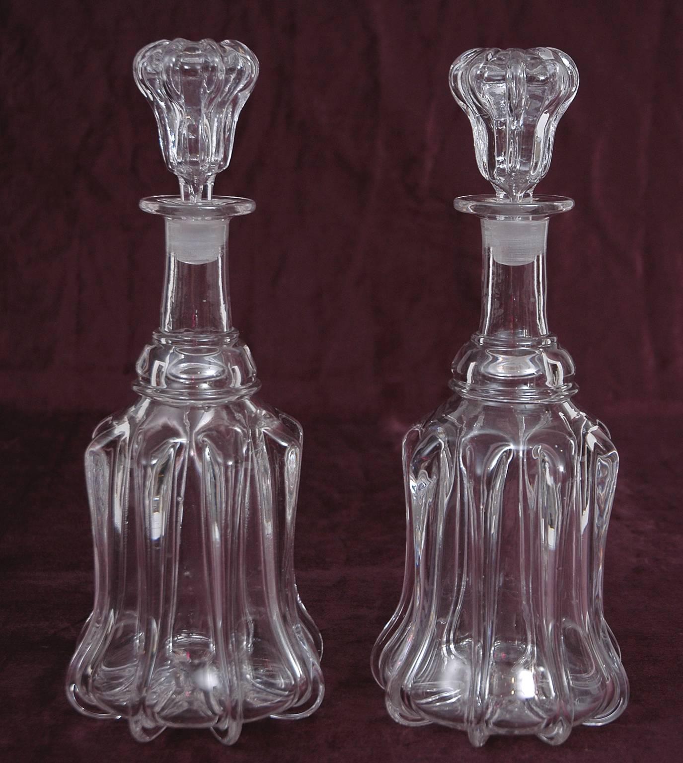 A fine pair of octagonal, molded blown-glass decanters for port, sherry and Madeira in shouldered form with stoppers. England, circa 1730. A popular drink of the wealthy during the 1700s, these fortified wines were decanted to remove any sediments,