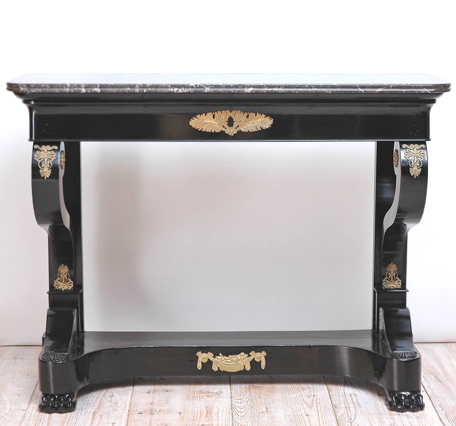 A Napoleon III ebonized console with original Negro Marquina marble top, with one drawer and resting on concave plinth with carved lions' paw feet. Offers original bronze doré´ mounts of peacock feathers (a reference to Hera, the wife of Zeus),