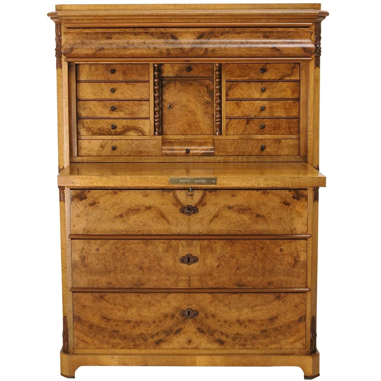 A handsome fall-front secretary in quilted and burled walnut with figured walnut, book-matched veneers. The subdued design is interrupted with small embellishments which include rope-turned columns flanking the interior desk cubby and carved