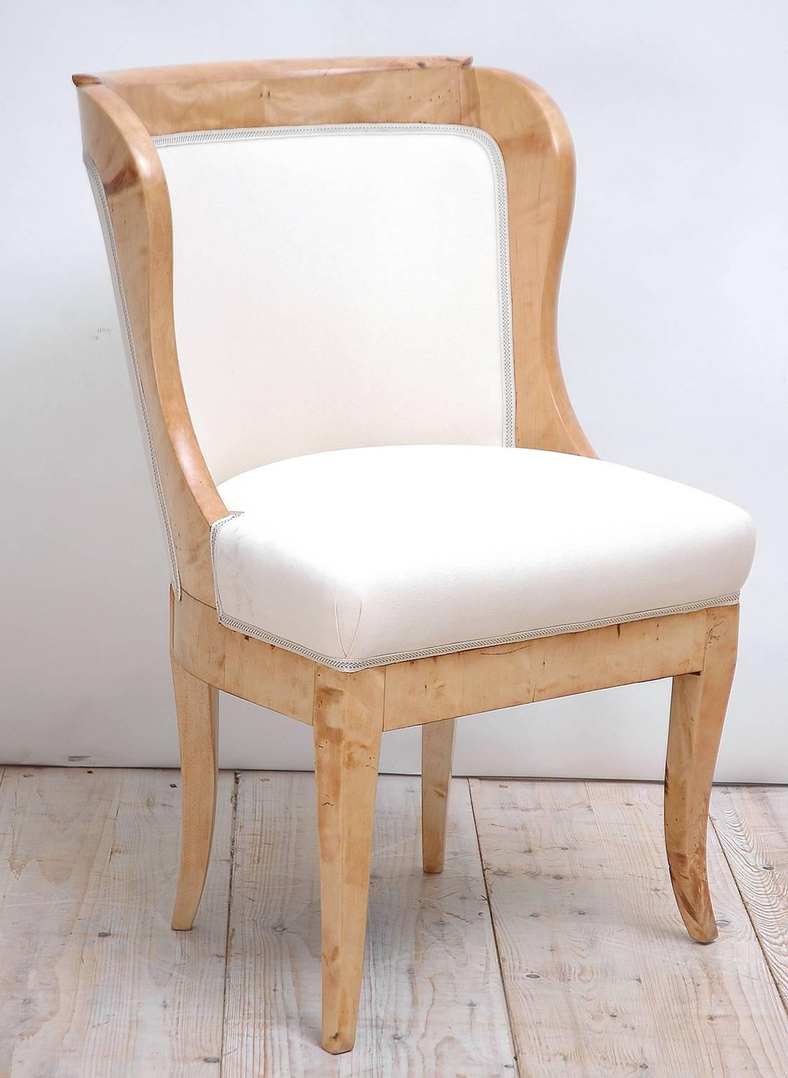 A beautifully proportioned Karl Johan/Biedermeier chair with rounded gondola back and tapered saber legs in a light birch with newly upholstered seat, interior and exterior back in a cream-colored Robert Allen cotton twill with Beacon Hill gimp,
