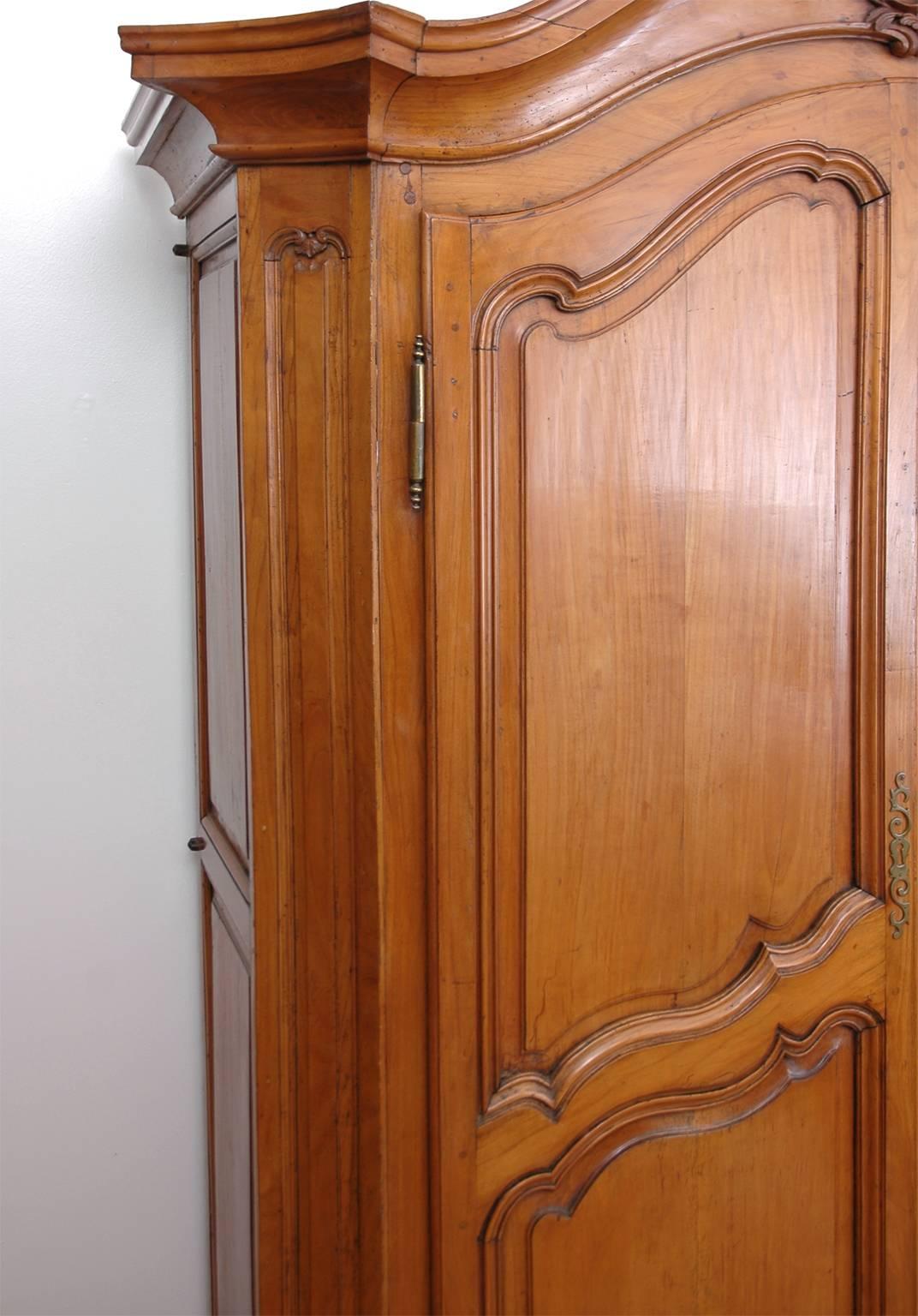 A handsome Louis XV armoire in wild Cherrywood with arched crest molding and carved bonnet, two doors that are also arched and paneled, carved apron and escargot feet, France, circa 1750 with later additions.
Measurements: 73