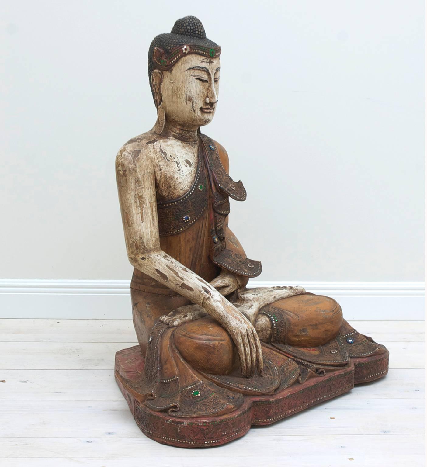 This youthful, sweet-faced image of the Buddha wearing a robe elaborately folded, edged and decorated often with inset mirror glass, is known as a ”Mandalay Buddha” from Burma or present day Myanmar.  This form of Budha was prevalent from 1855-1945.