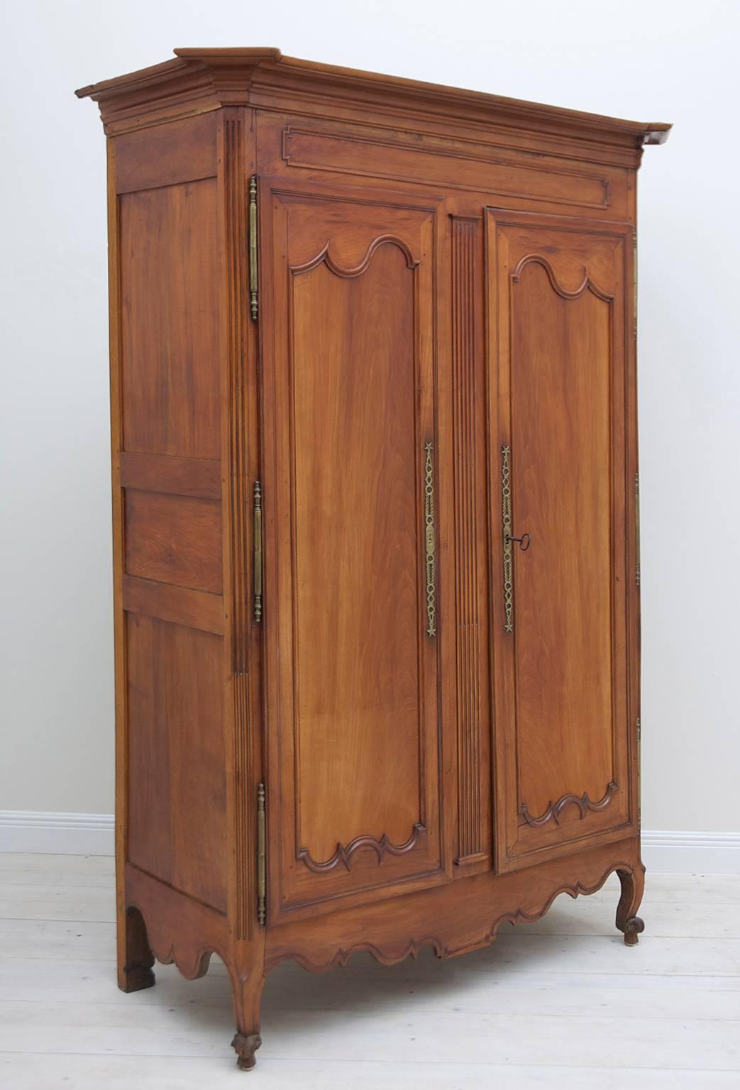 A handsome Louis XV armoire with stately proportions. Offers straight, stepped crown molding with chamfered corners, curvilinear molded inset panels on two doors, fluted astragal that is attached to one of the doors which allows both doors to open