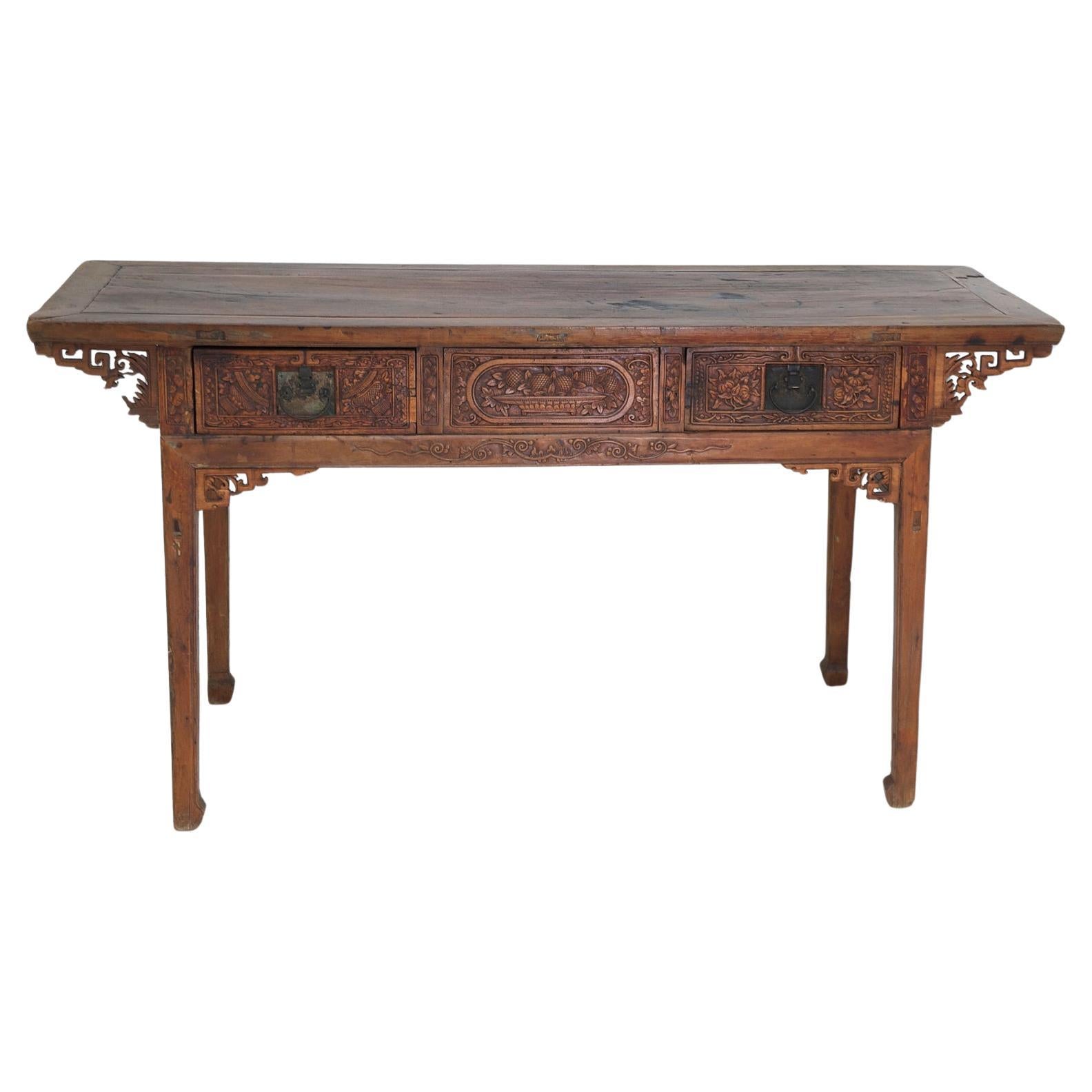 A very lovely 18th century Chinese altar table embellished with fine carvings on drawer fronts and spandrels and resting on inverted hoof feet. Offers two drawers on one side and one on the other, with carvings on both sides - making this a