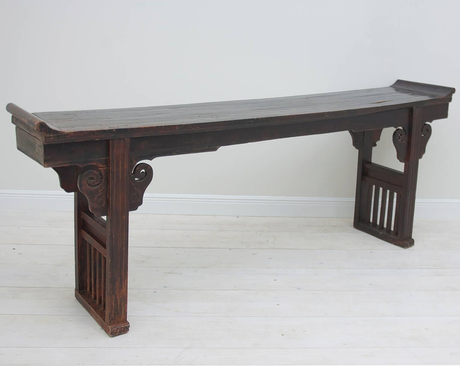 A long altar table in elm wood with recessed top, with inverted ends, on box trestle base with carved cloud forms on spandrels. Has traditional unmitered bridle-joint construction. Jiangsu Province, China, circa early 1800s. 

Measures: 97"