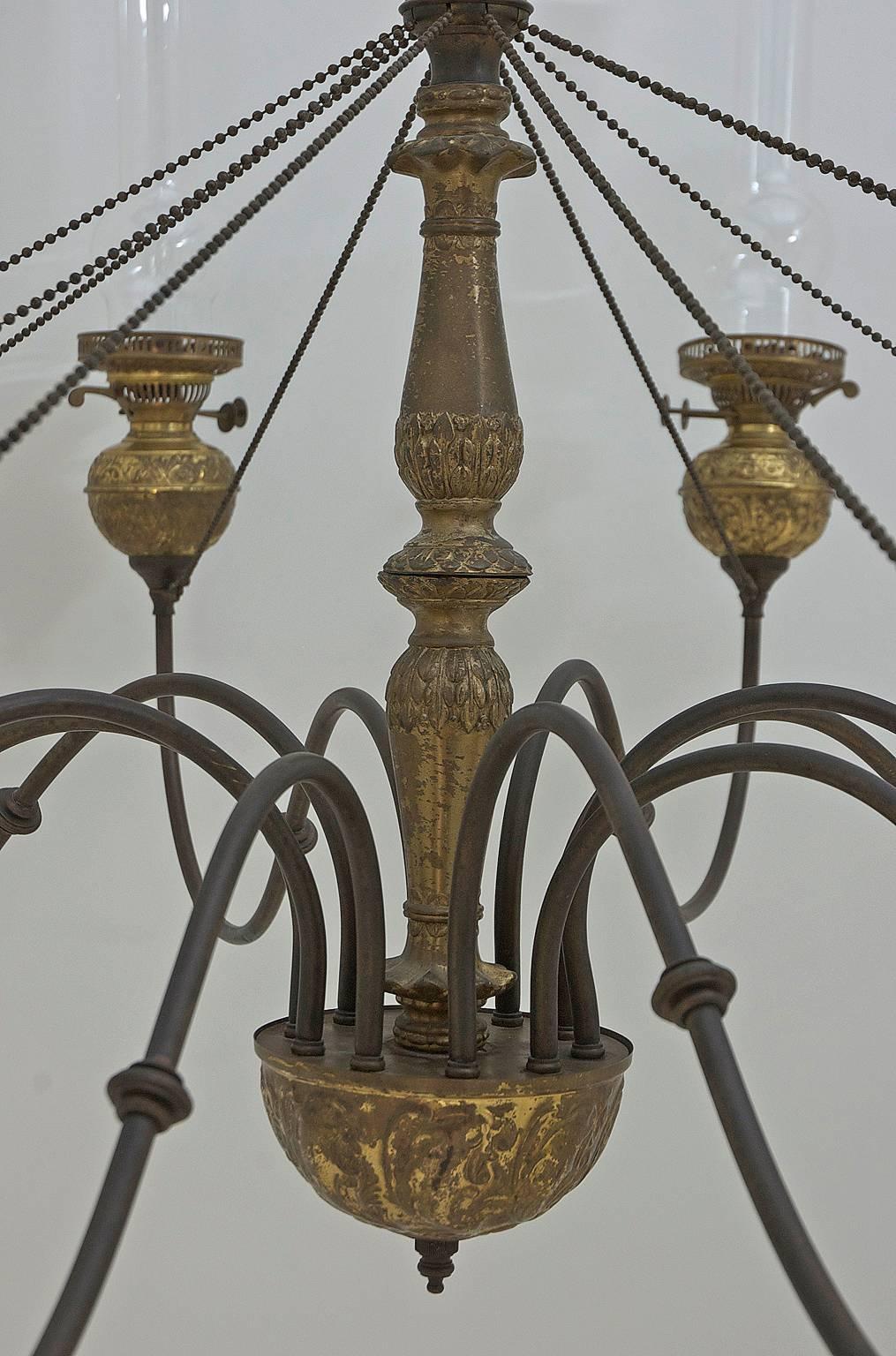 A ten-light chandelier in hand-hammered brass with glass chimneys. England, circa 1860-1880. Manufacturer stamped on gas cocks. "Made in England Duplex."
This chandelier was originally a Duplex double burner Paraffin Lamp which employed