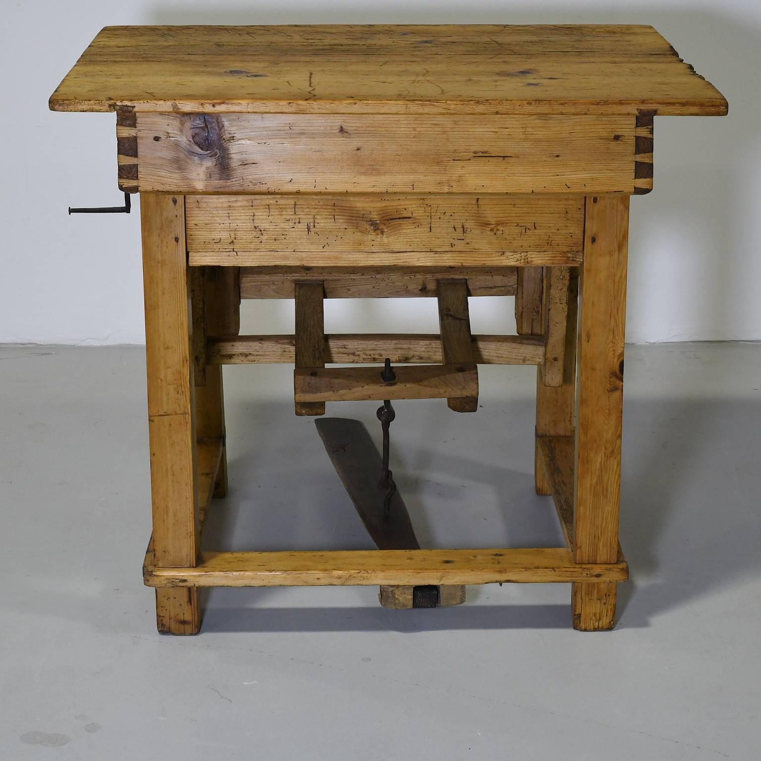 A rare piece consisting of a pine table doubling as a mangle, with the rollers and foot press housed in the interior, iron handle on the side, and the top opening on a slant to provide a surface from which to feed or draw out the fabric. Pegged