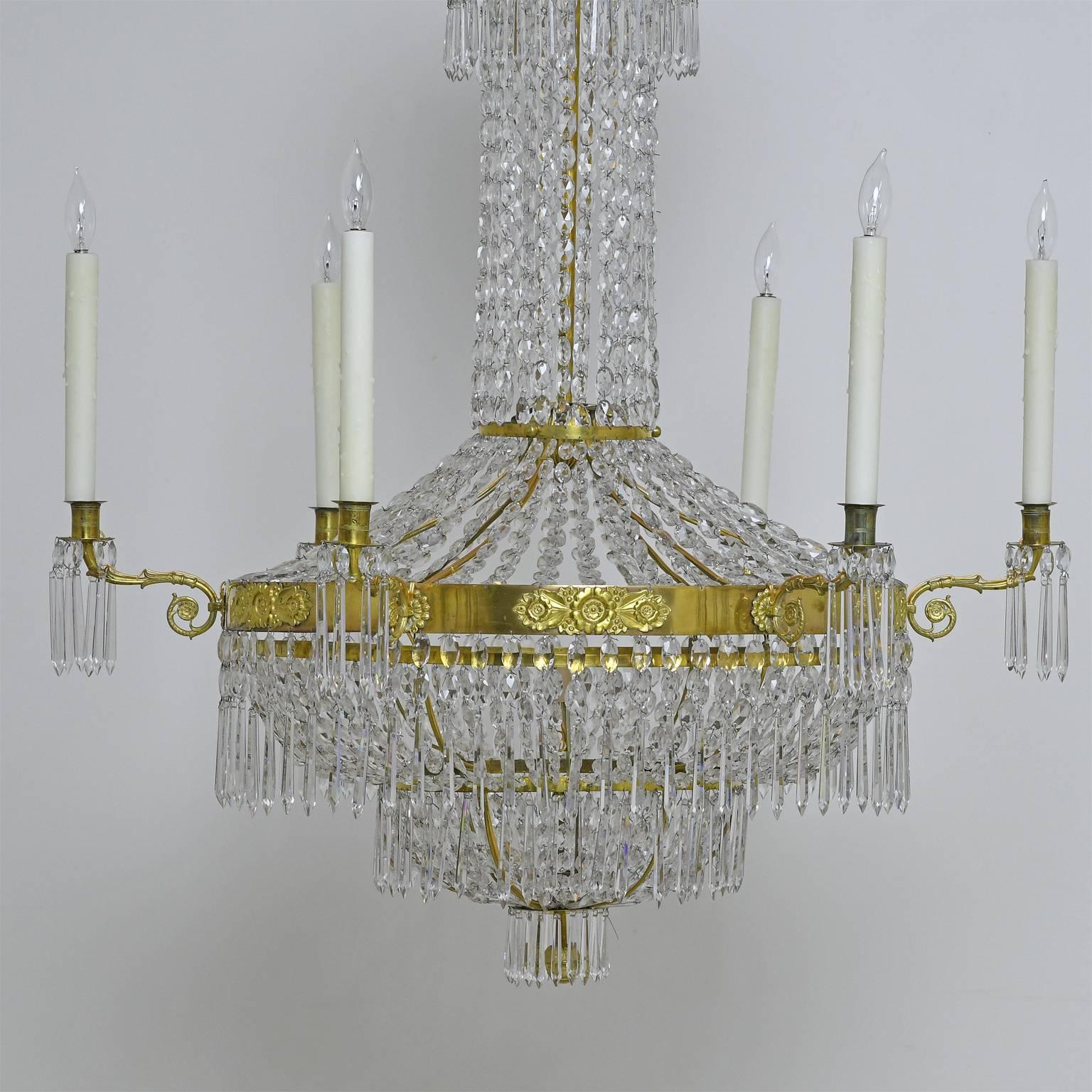 A very fine and large-scale Antique Gustavian or Karl Johan Empire crystal chandelier with gilt bronze armature featuring a center ring with thinly pressed rosettes and foliage between the six candle holders. The diminishing brass rings which appear