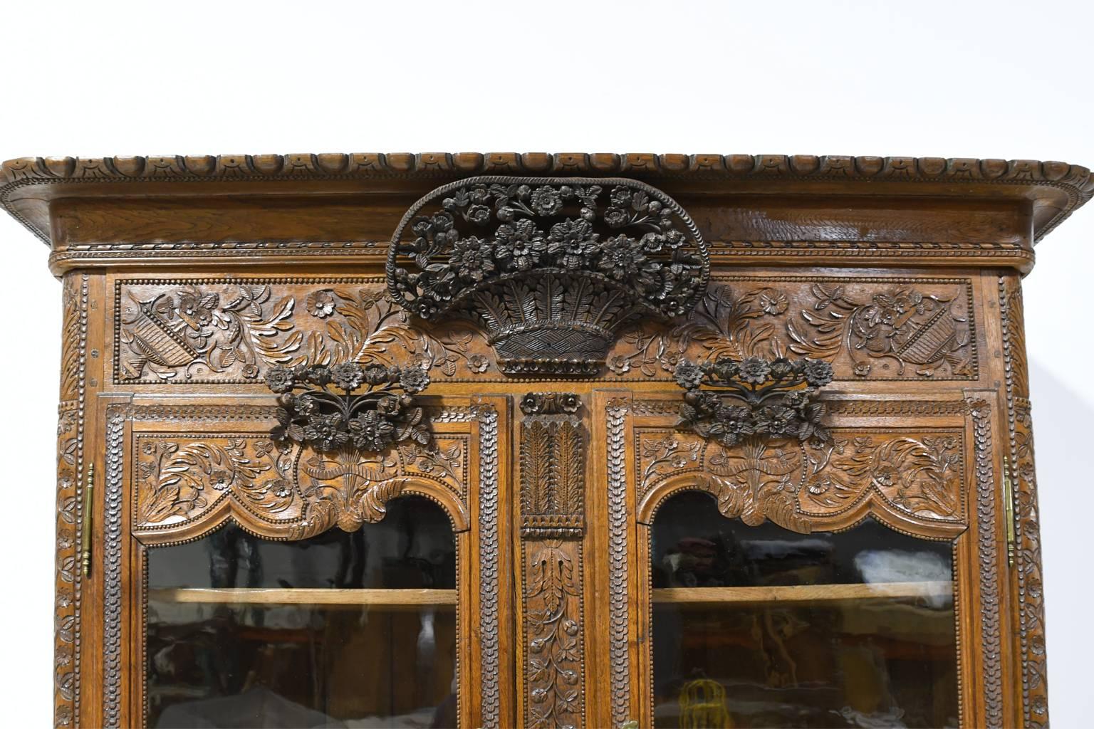 A lavishly carved wedding piece, this oak buffet a deux-corps from Normandy, is embellished with foliage and flowers in carved relief, as well as offering beautifully-articulated applied carvings in high relief as seen in the central flower-filled