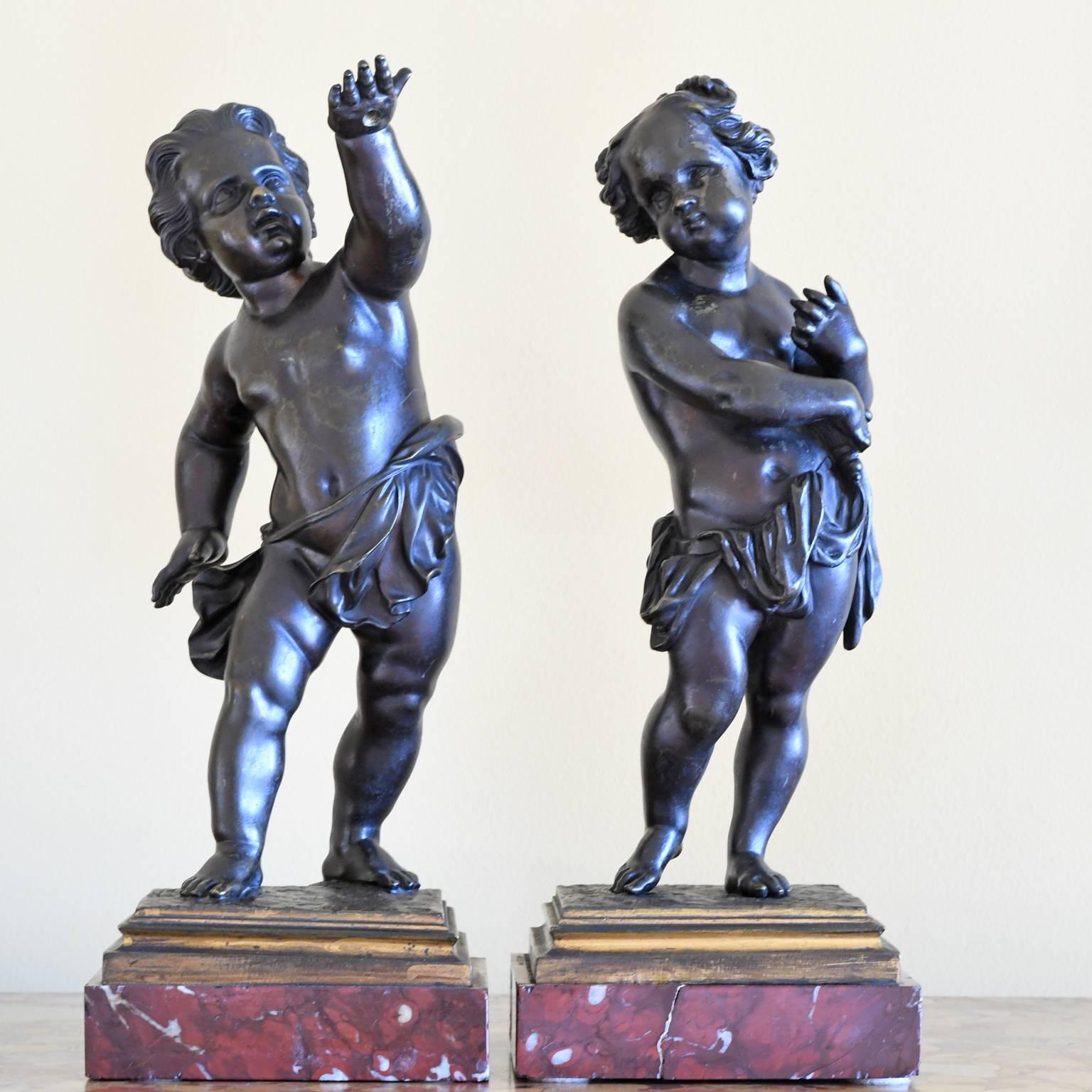 A pair of cast bronze cherubs or putti standing contrapposto on a square red marble base, France, circa late 1800s.
Note: These charming cherubic figures were probably used in combination with candelabras based on the markings on the backs of each