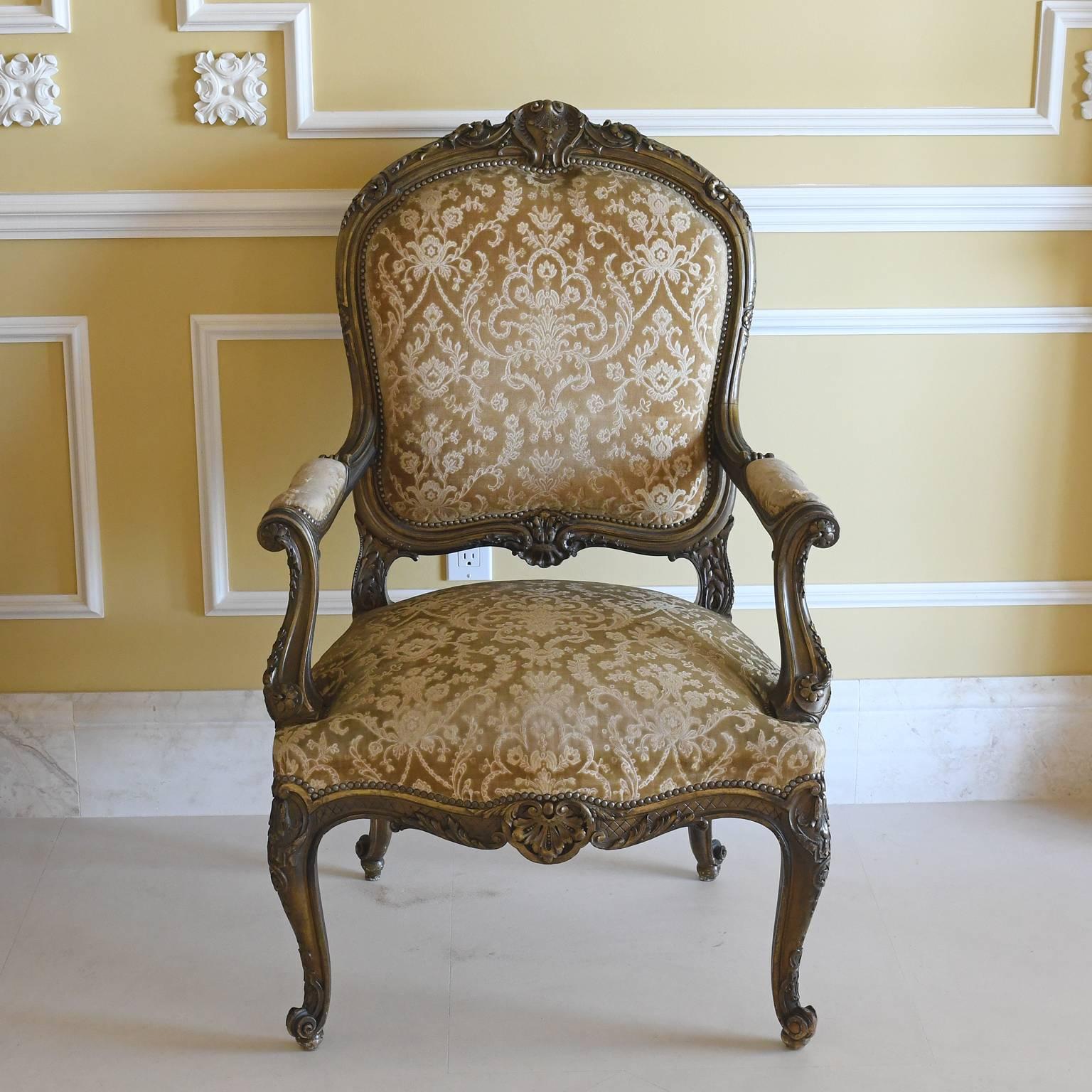 A pair of late Napoleon III fauteuils or armchairs in a hardwood with a burnished gold overtone. In the Louis XV style, chair frames offer carved cabriole legs with escargot feet, scroll arms and carvings on center crest and bottom rail of back and