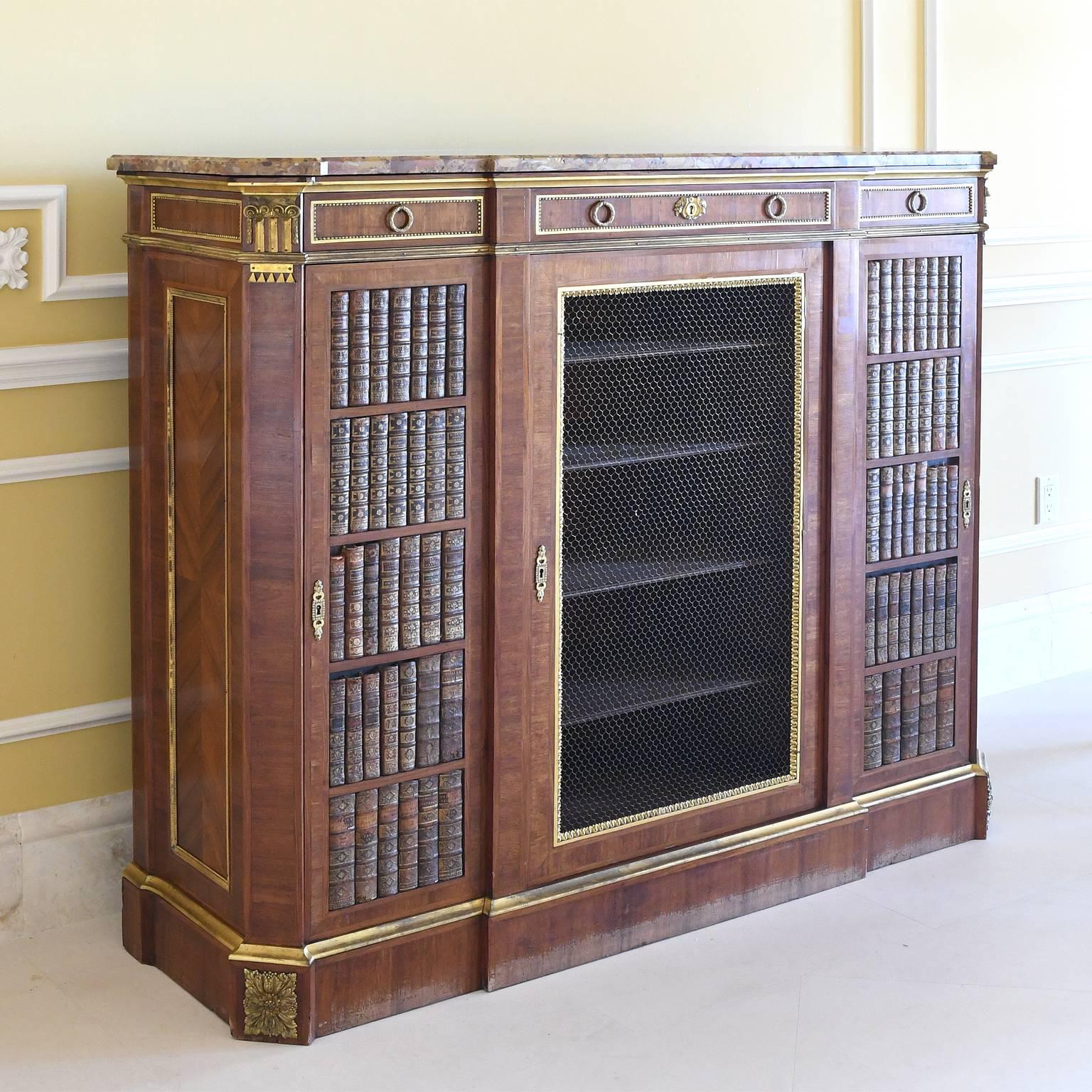 A very fine Napoleon III cabinet or bookcase in the Louis XVI style with original marble top, bronze doré ormolu, antique 18th century French book bindings on the end doors and a brass wire on the center door (that has interior hardware for a