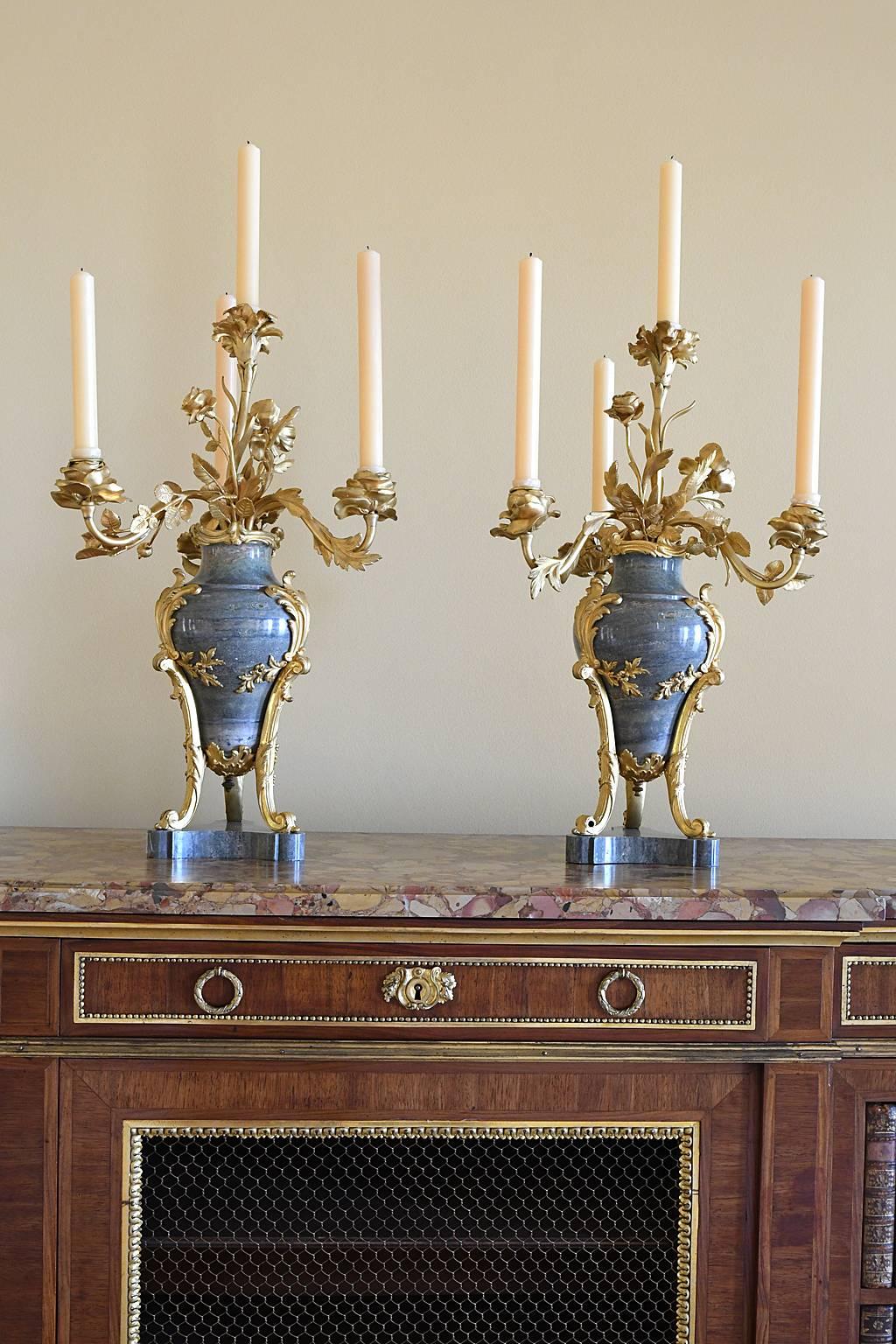 A lovely pair of French Louis XVI style candelabra with turned light-green-marble vase resting on tripod marble base with bronze d'ore ormolu supports. Each features beautifully-articulated gilt bronze foliage and flowers, with four candle arms