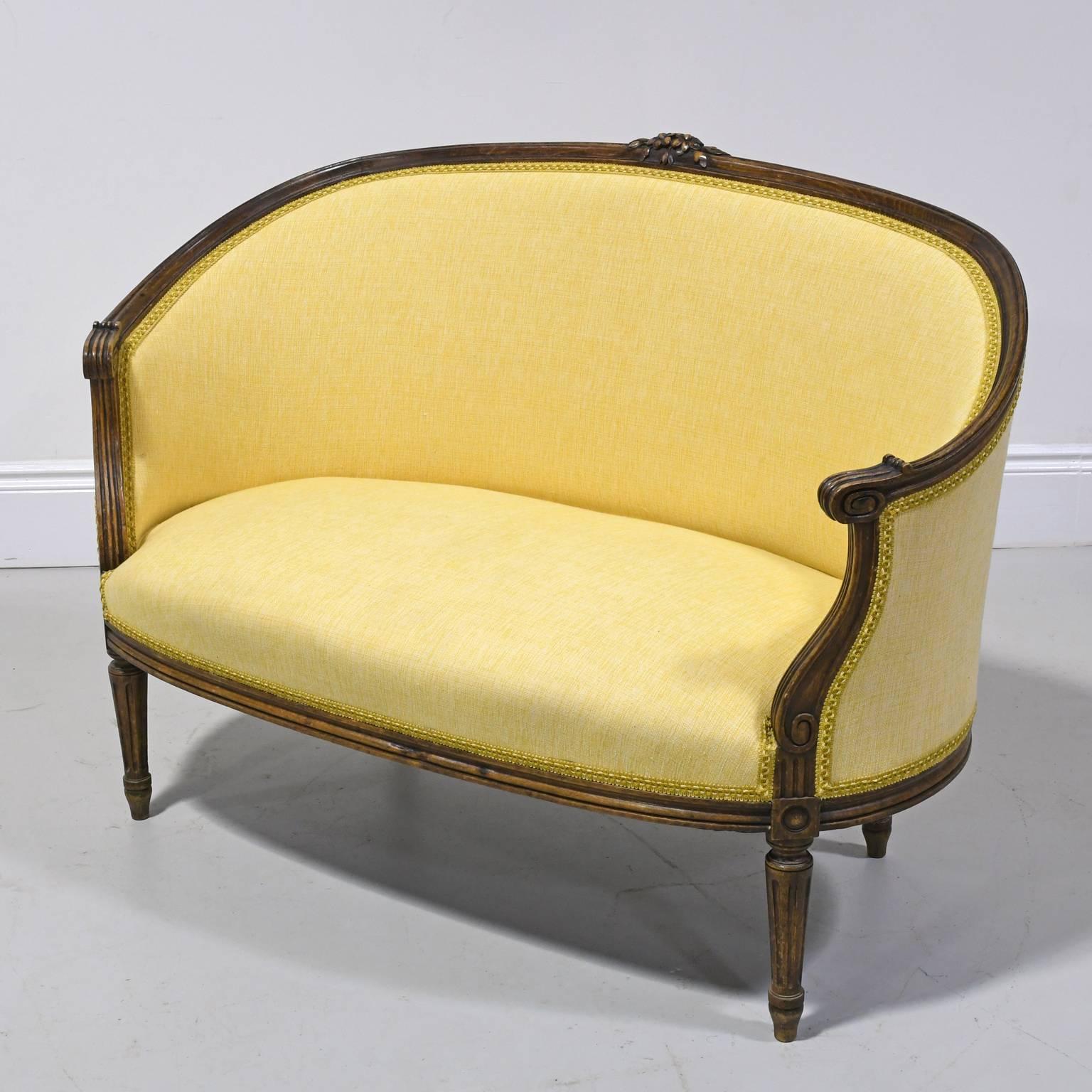 A lovely Louis XVI style canape or loveseat with walnut frame in gondola-form with upholstery, carved floral crest, scrolled arms, and resting on turned and fluted legs, France, circa late 1800s.
A beautiful addition at the foot of a bed, in a foyer