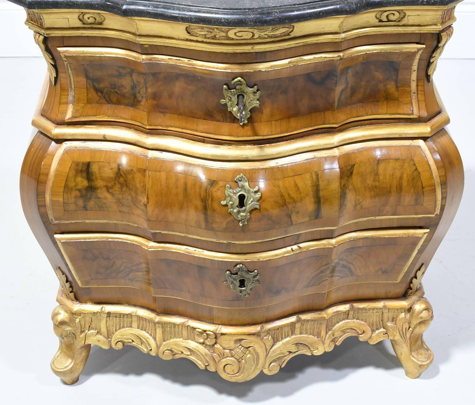 A very lovely Rococo style chest with bombe front in walnut, with black marble top and parcel-gilt details, offering three drawers, Denmark, circa mid- late 1800s.
Measures: 28