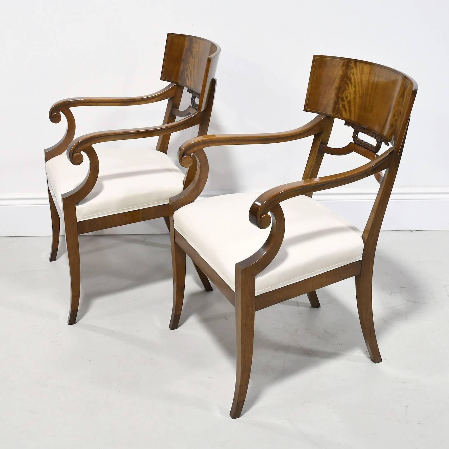 A very handsome and refined pair of Karl Johan-style Empire Klismos armchairs with saber legs from the Art Deco period in Sweden, circa 1920s. These chairs are exquisitely made using Cuban mahogany, Fine joinery techniques, and offer a wider seat