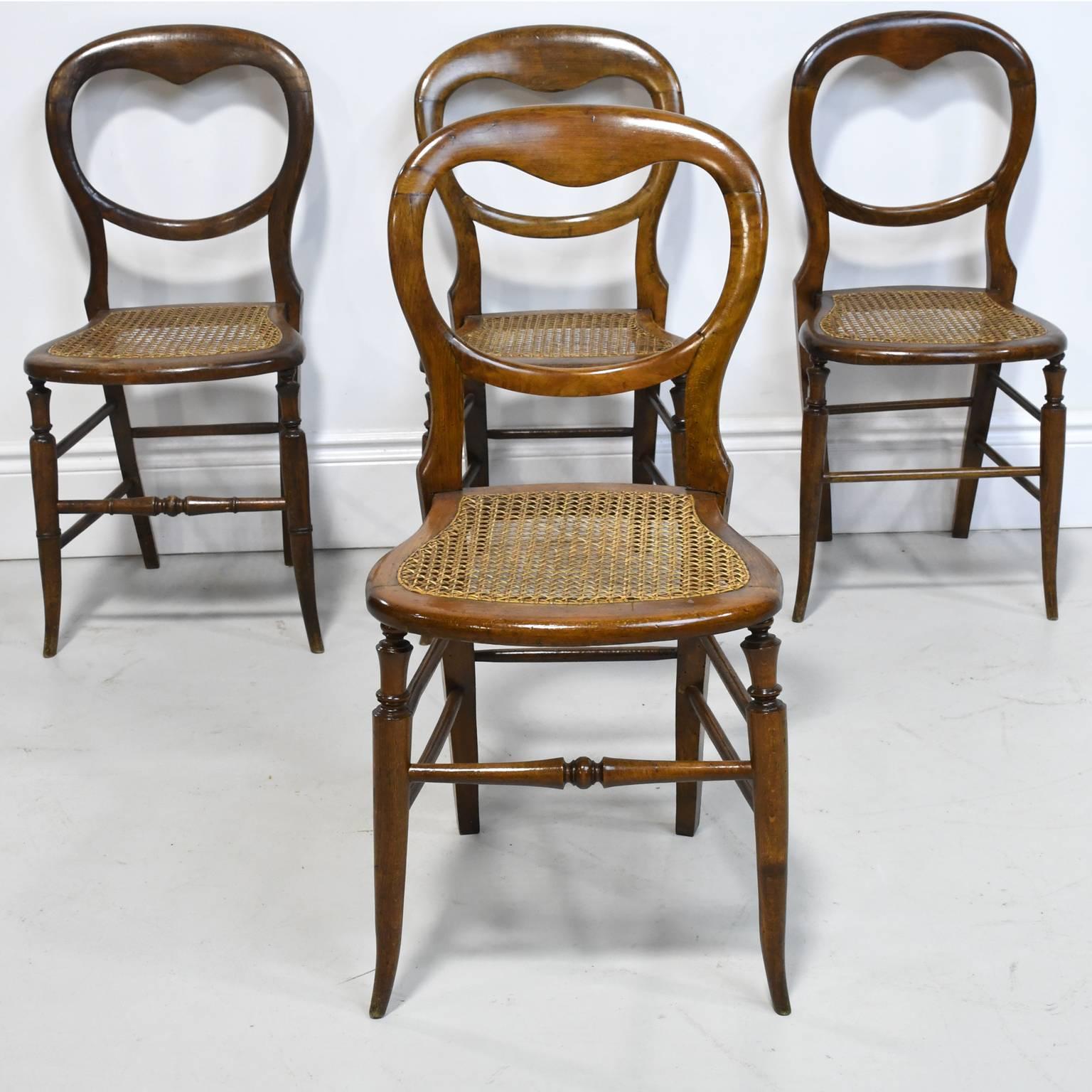 A charming set of four Louis Philippe dining chairs with balloon backs, splayed legs and cane seats, France, circa 1845. 
Measures: 16" wide x 18" deep x 32 3/4" high.