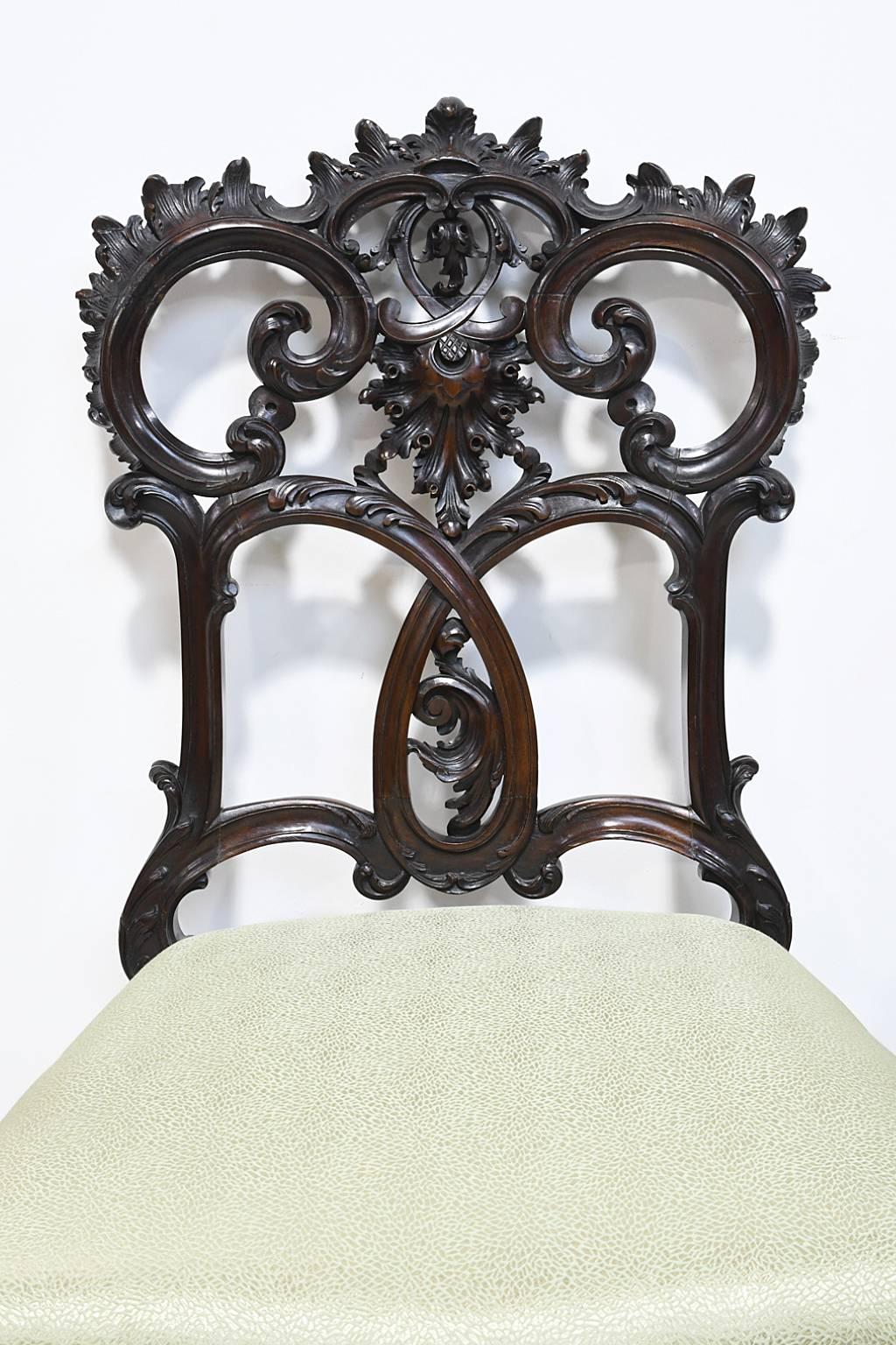 An exquisite pair of very finely carved Rococo-style chairs in mahogany with elaborate rocaille embellishments throughout. The high quality and well articulated carving suggest that they are NY made and can be attributed to or were influenced by the