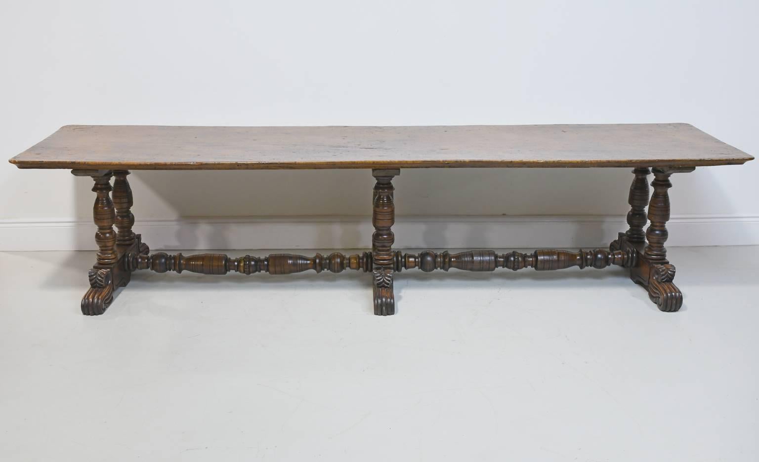 Made with a single plank of wood on the top, this extraordinary Spanish Colonial dining table is from the Philippines and features a beautifully turned and carved trestle base with stretcher, all made of Molave, an indigenous hardwood, circa early