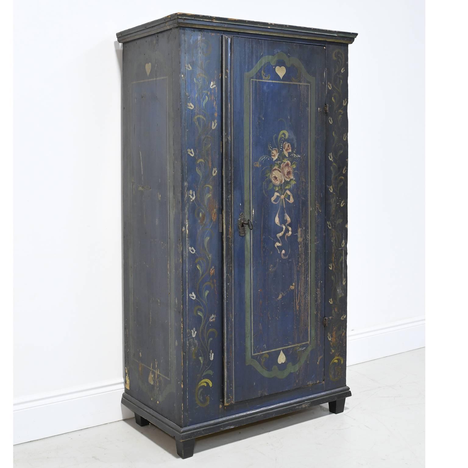 A very lovely dowry armoire with the original blue background paint embellished with hearts, foliage and a bundle of pink roses tied with a pink ribbon. Austrian or German, circa late 1700s to early 1800s. Interior offers five adjustable