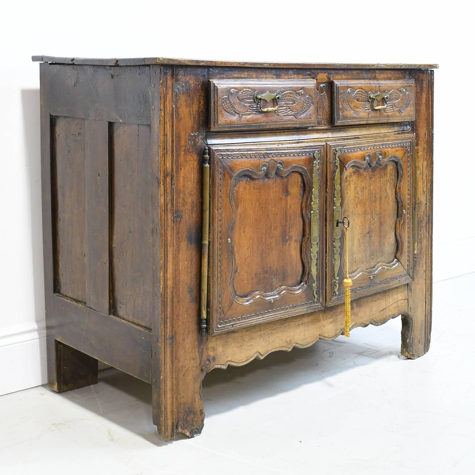 A mid-18th century buffet or sideboard in walnut with two cabinet doors with curvilinear, recessed panels below two drawers with carved depictions of birds. Has original brass key-plates and hinges, with one working key, France, circa 1750.
Makes a