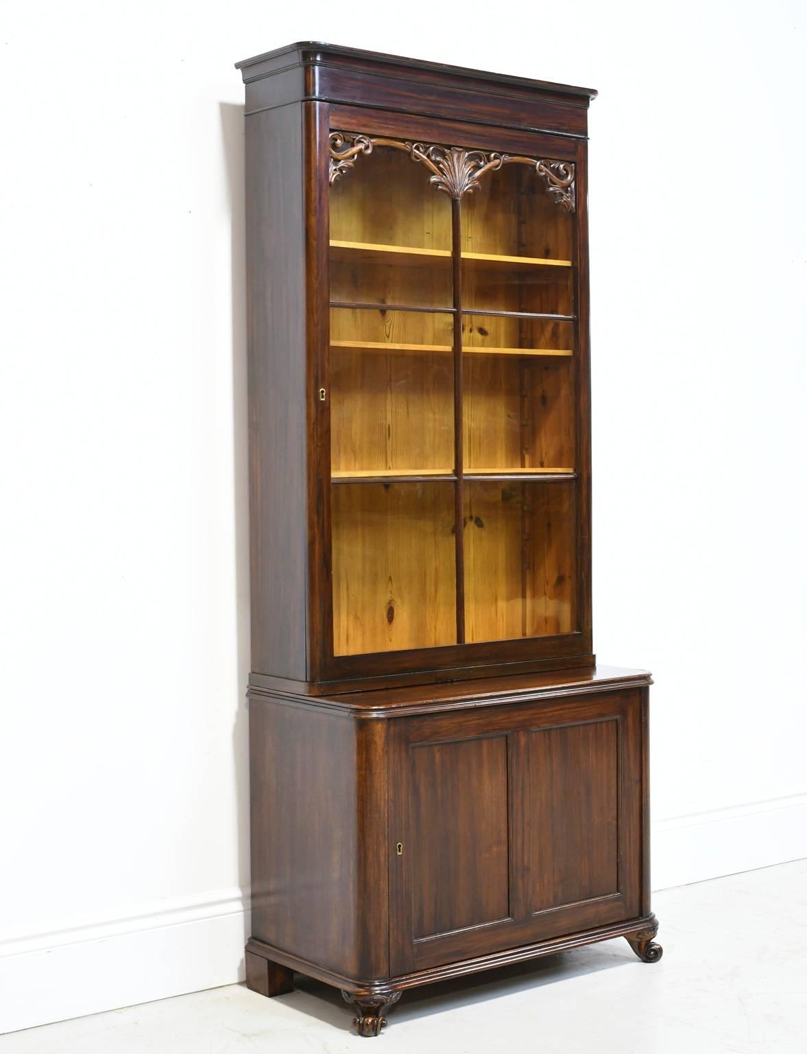 From the reign of Danish King Christian VIII a beautifully proportioned and unusually narrow vitrine or bookcase in mahogany with mullioned door and arched fretwork & original glass, above paneled cabinet with carved escargot feet. Has three