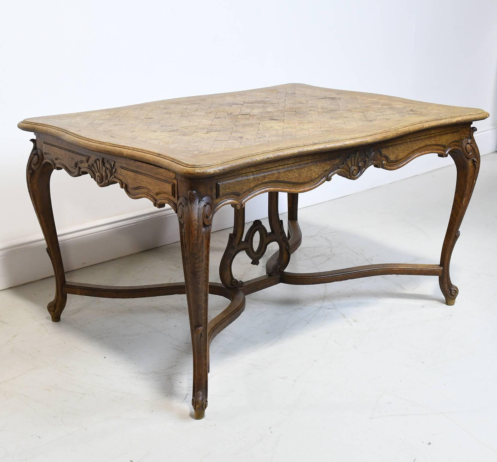 This especially beautiful French Provincial dining table in the style of Louis XV is in oak with an undulating parquetry-inlaid top with drawer supports at either end that pull-out for two leaves (that would need to be made) that extend the table's
