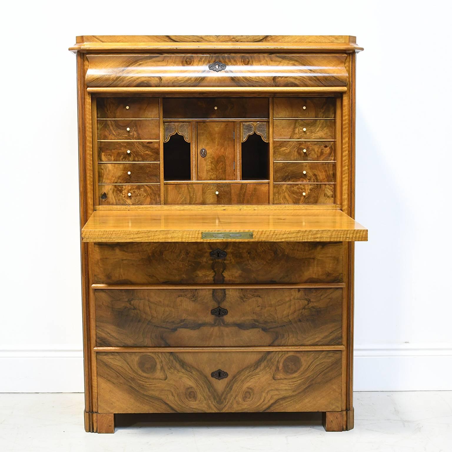 This exceptional secretary desk in figured and book-matched walnut is from the reign of Karl Johan of Sweden and is truly a work of art. It offers one drawer above the fall-front desk with small interior drawers, open and closed cubbies, and with