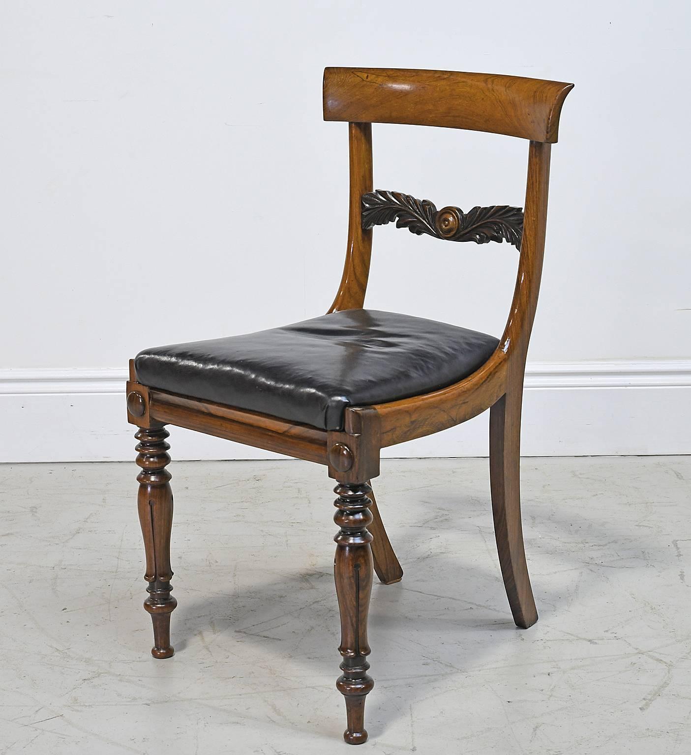 A handsome William IV Regency side chair in rosewood with concave back rail, well-articulated carved mid rail, turned front legs, splayed back legs and black leather slip seat, England, circa 1830. Chair offers a solid construction, as well as