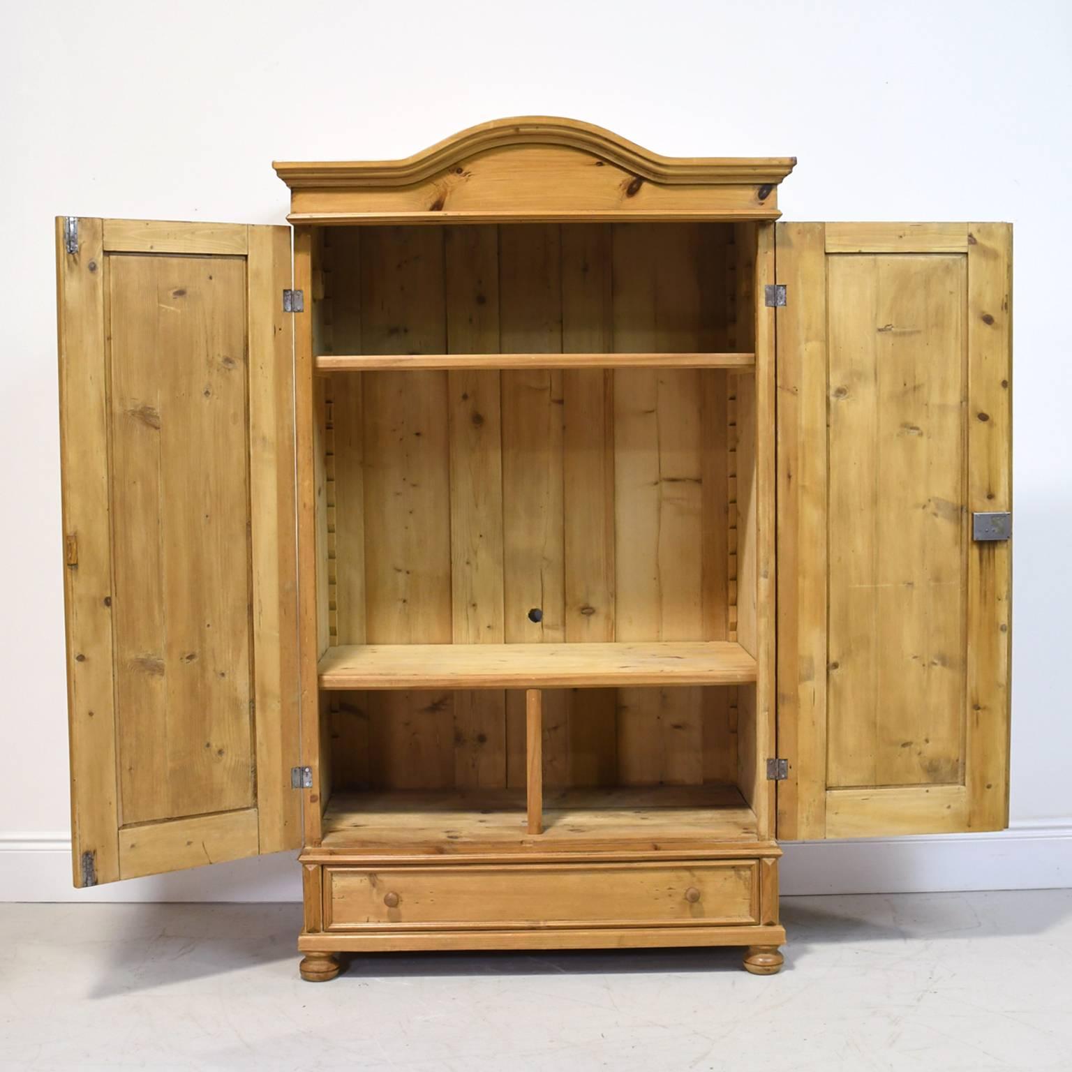 From the Austro-Hungarian Empire, a lovely pine armoire with curved bonnet, two doors with recessed panel and original nickel key plates, exterior drawer with turned wooden knobs, and bun feet. Comes with working lock and key, circa 1860.
A great