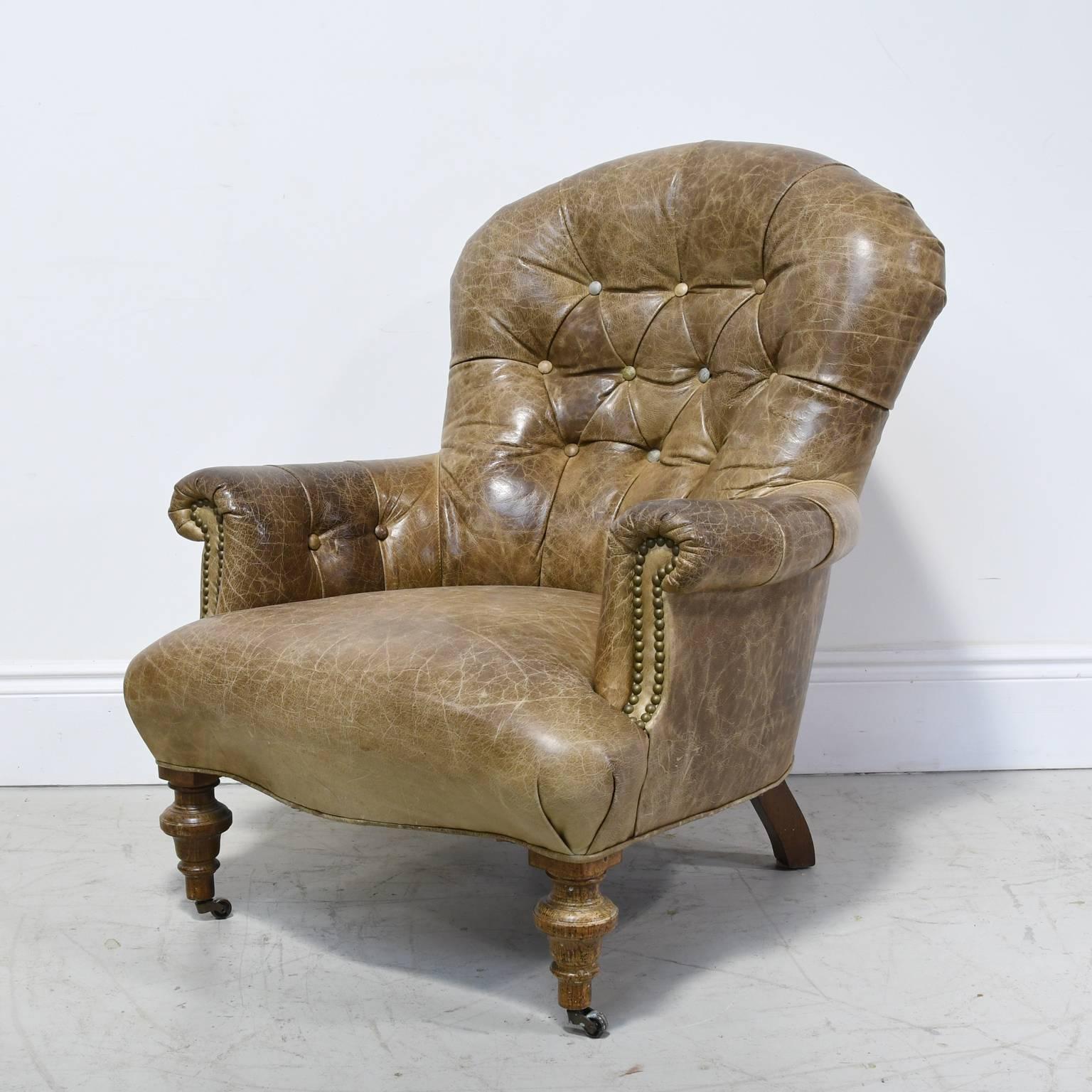 A handsome and comfortable brown-leather club chair with scrolled arms, tufted back and turned front wooden legs on casters with splayed back legs
Measures: 31 1/2