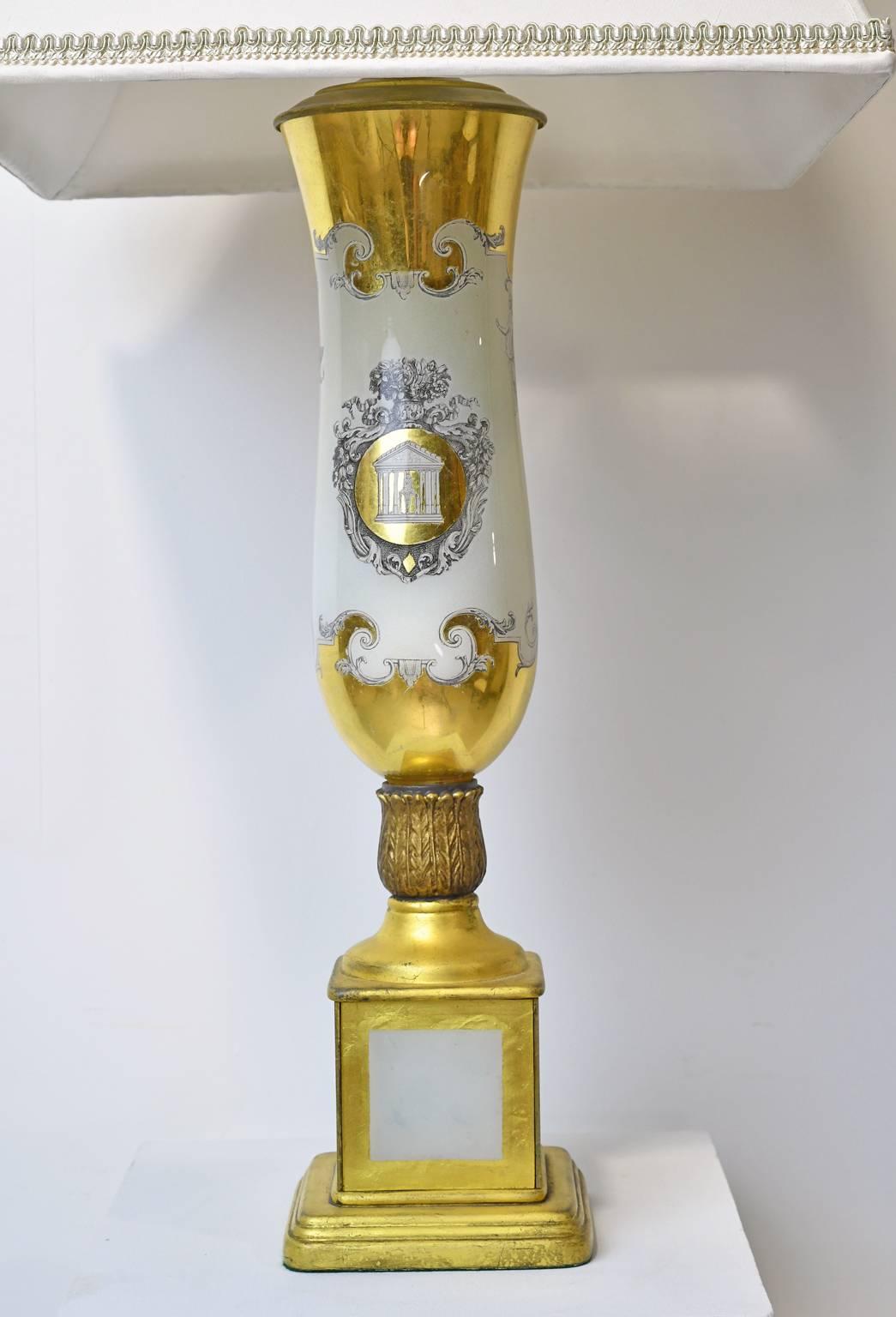 A decorative pair of 20th century white porcelain lamps with vase-form resting on square pedestal base in the Paris ware style, with decorations that include gilded elements and a cartouche with a Greek temple. Shades are included. Possibly French,