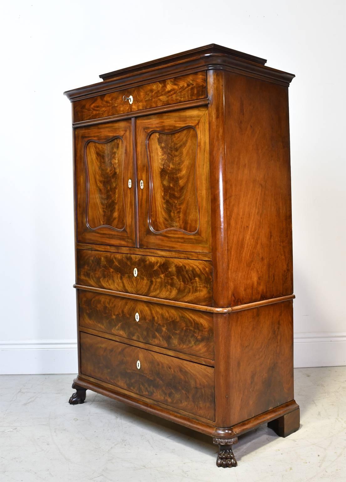 A very handsome Biedermeier silver or liquor chest in book-matched flame mahogany. Denmark, circa 1835. Features a pedestal top over a single drawer followed by cabinet doors that open to an open storage area with three small interior drawers. The