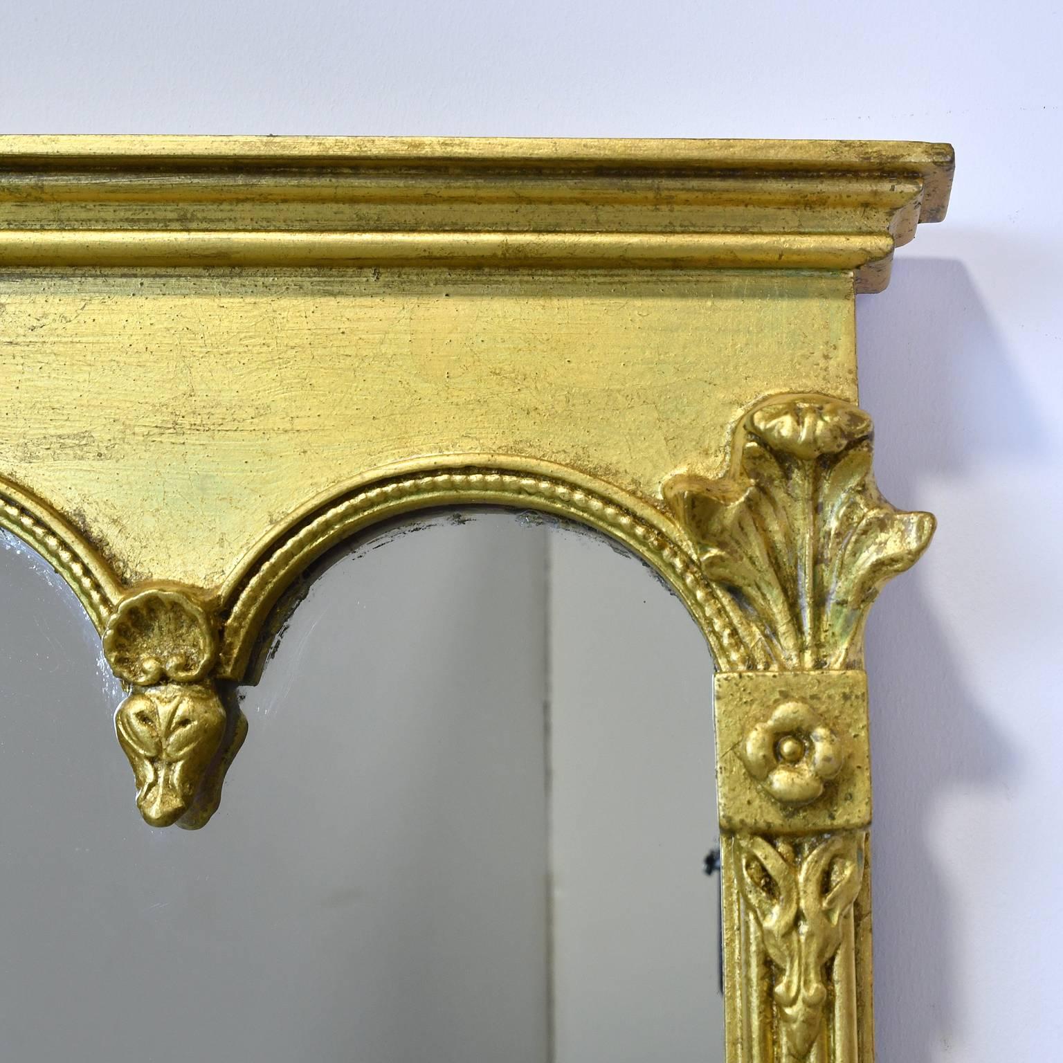 A large decorative mirror in gold leaf that is in a rectangular horizontal form, ideal over a fireplace mantel or sideboard. Embellishments include reeding, rosettes, foliage, flowers and the Prince of Wales feathers, American, circa
