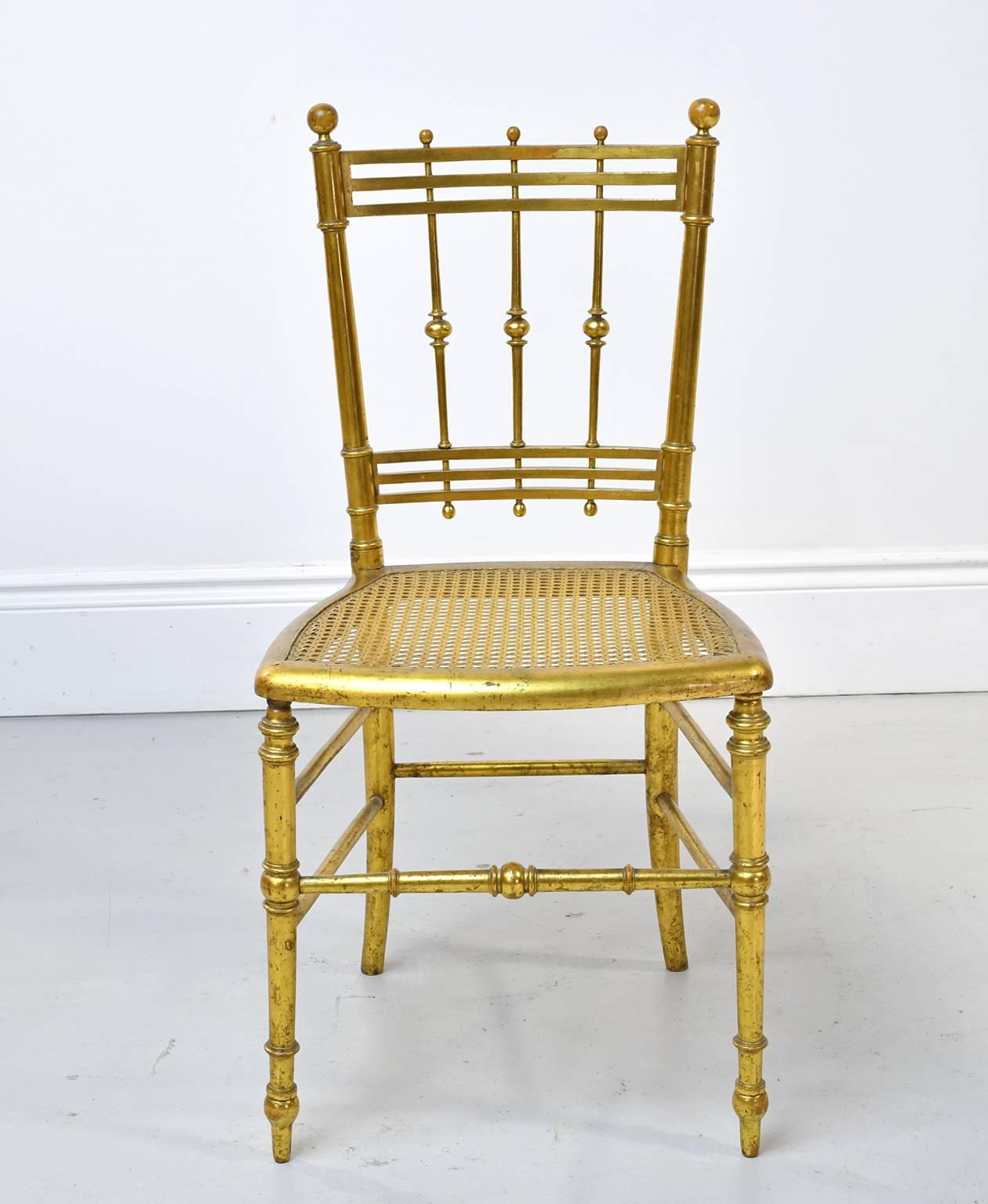 A very lovely pair of Belle Époque dining or salon chairs in giltwood (gold leaf applied to wood) with vertical & horizontal slats along back, ball finials, turned front legs & stretchers, and woven cane seat. France, circa 1910.
Wonderful in a