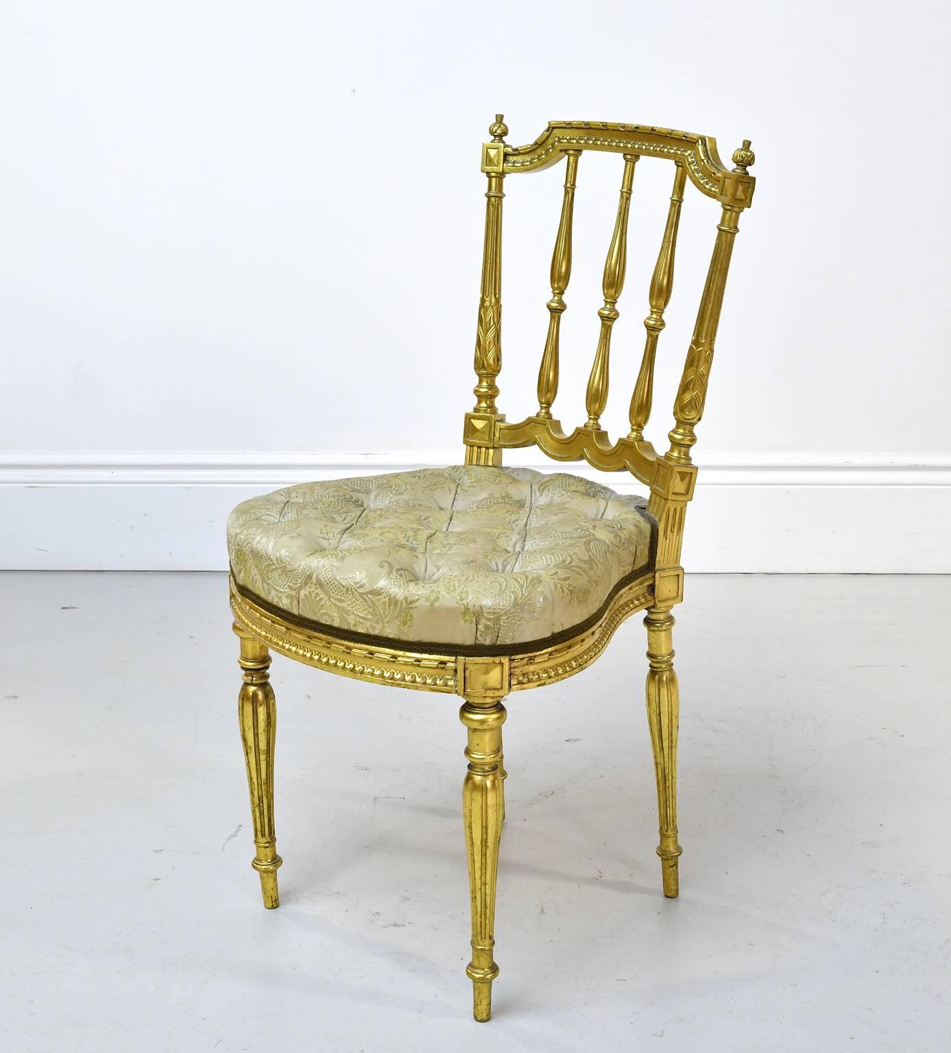 A lovely Louis XVI style salon chair in giltwood (gold leaf applied over wood) with spindle-back, turned & reeded legs, carved & round-shaped seat rail with tufted upholstery. Belle Époque France, circa 1890-1900. A beautiful chair for a dressing