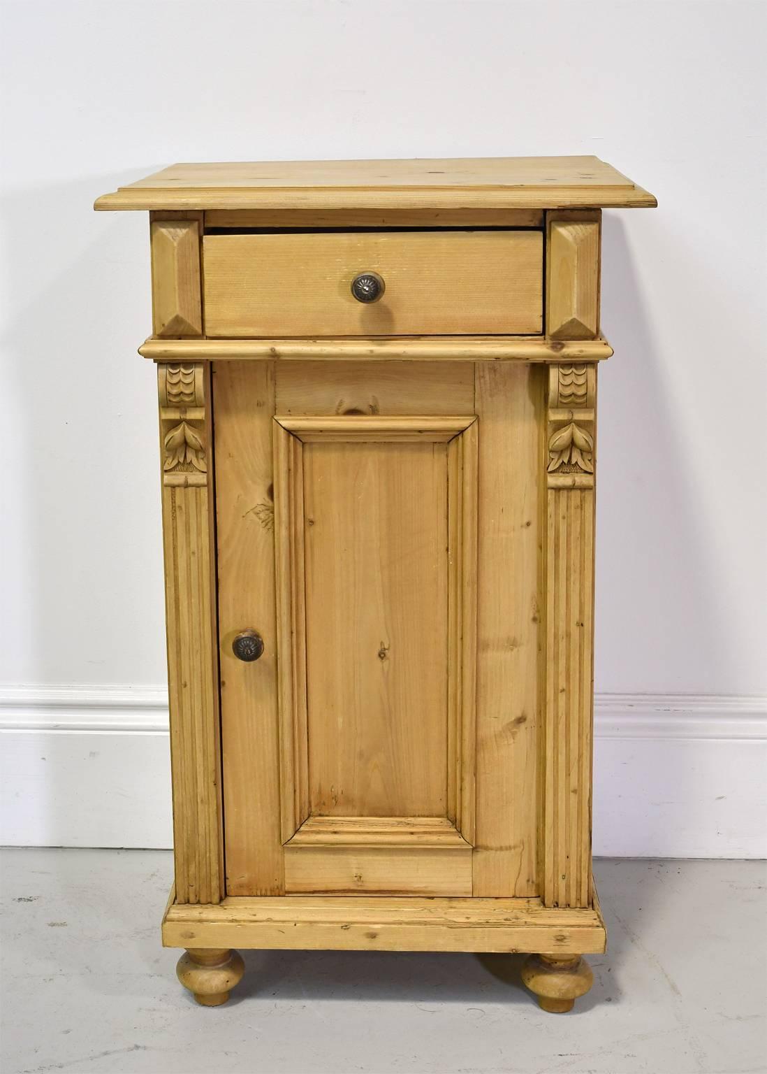 A very lovely small nightstand in pine with carved and geometric appliques, fluted pilasters on the sides, with a single drawer and paneled cabinet door, resting on turned bun feet, German, circa 1870. Original turned wooden knobs.

19" wide x