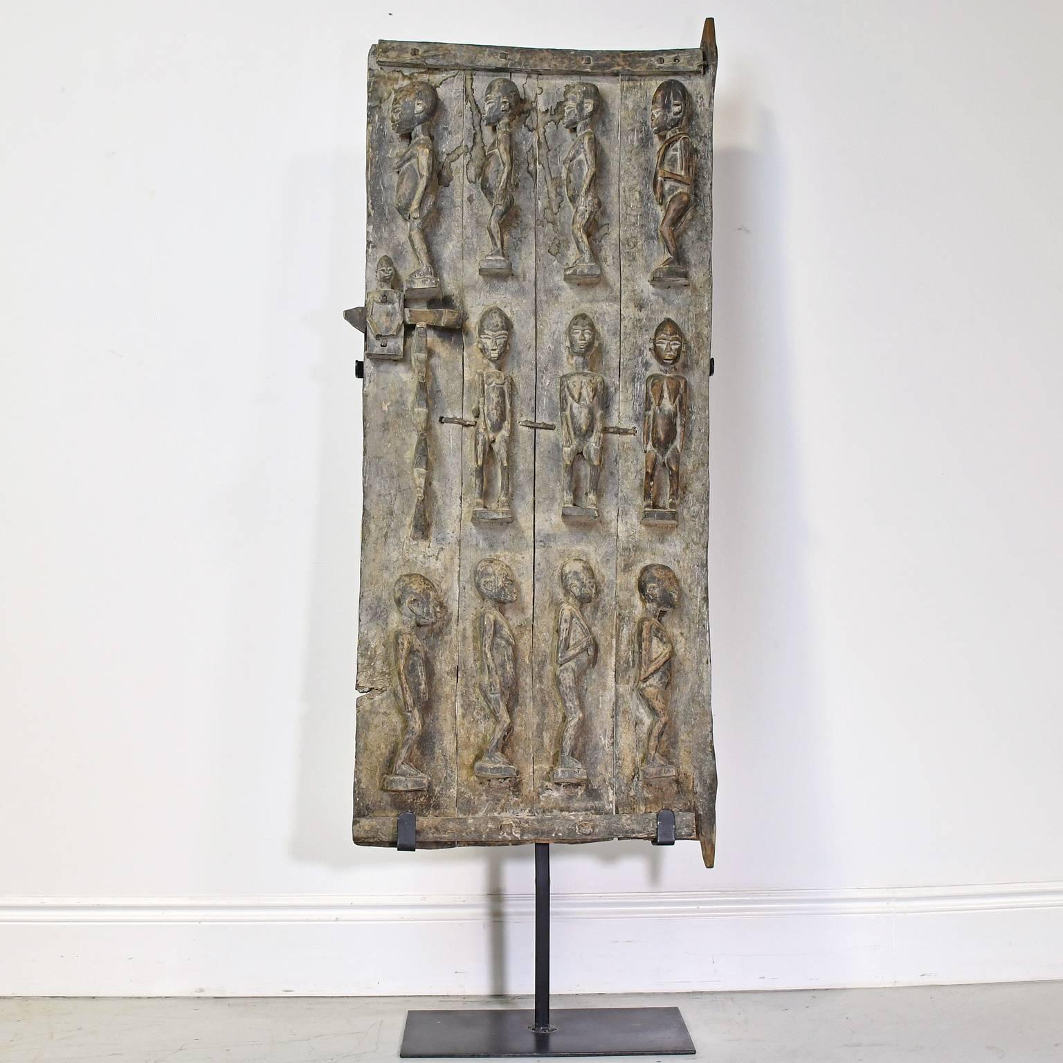 This impressive wooden door with carved relief depict three rows of Nommo ancestor figures. The door consists of four panels of wood that have been joined and pinned with iron straps and fasteners. The carving is exceptional. The doors are