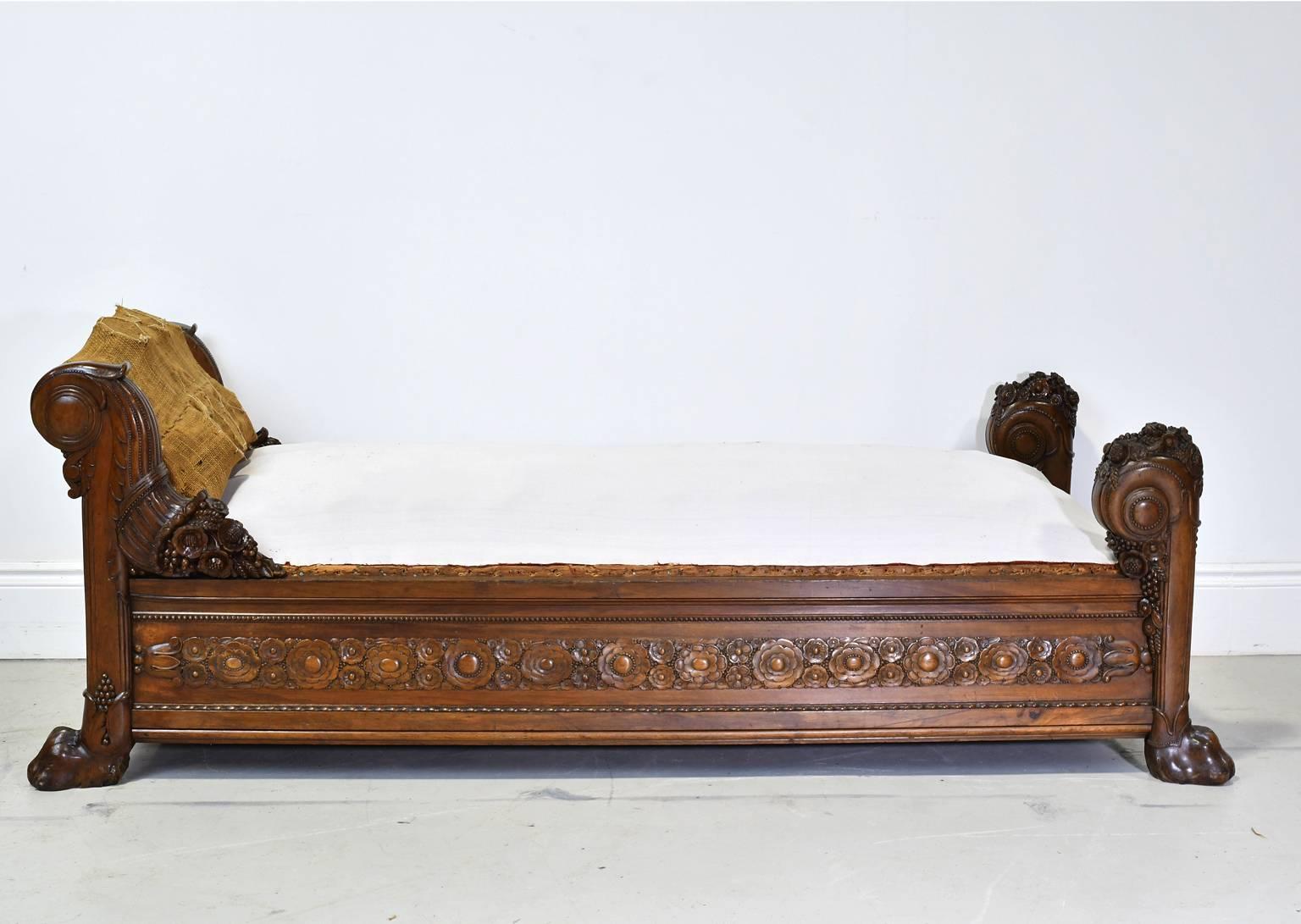 A very beautiful and opulent French daybed in mahogany from the Directoire period which preceded Napoleon's Empire and followed the reign of Louis XVI. The panels of the side and foot rails are carved with rosettes and the posts are scrolled and