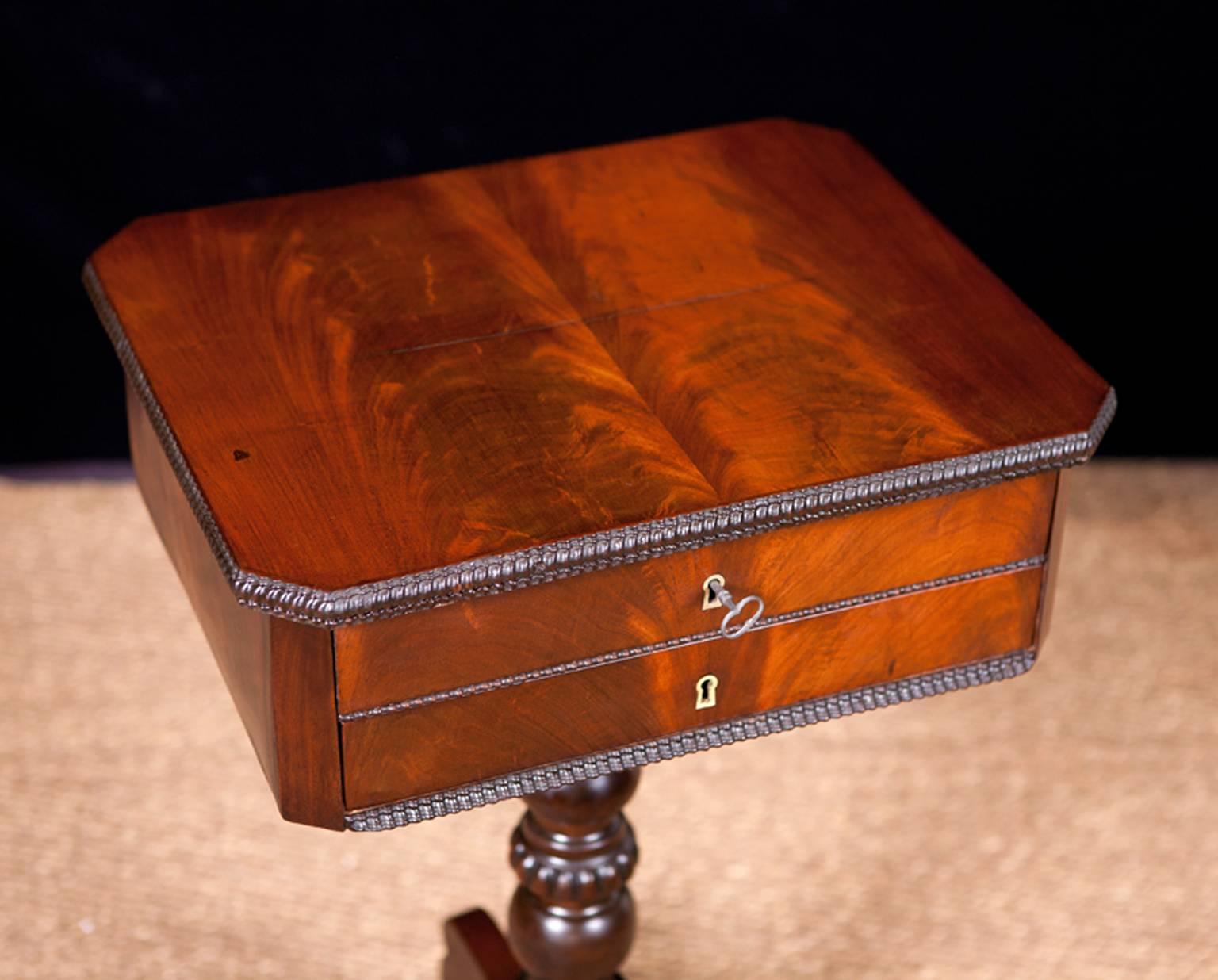 Perfect side or wine table next to a chair of sofa. A lovely sewing table in mahogany on turned & carved tripod pedestal base with two drawers & hinged lift-top. Top drawer offers lidded compartments decorated with marquetry inlays, and can be