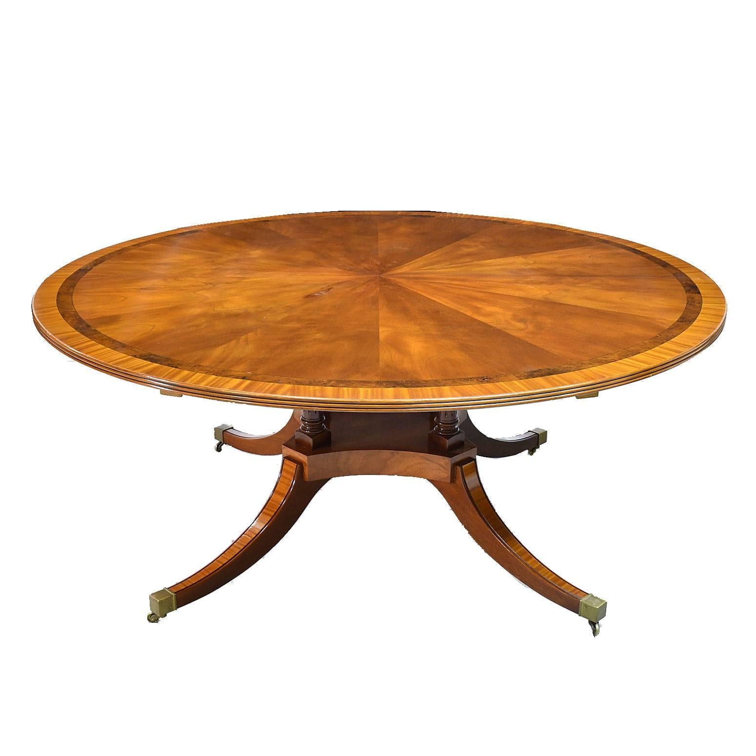 A very beautiful handmade 72" dining table in the style of the English Regency with a large round top in mahogany with crotch mahogany pie-shaped cross-band with satinwood bandings, reeded edge, yew wood and ebony line edges, resting on
