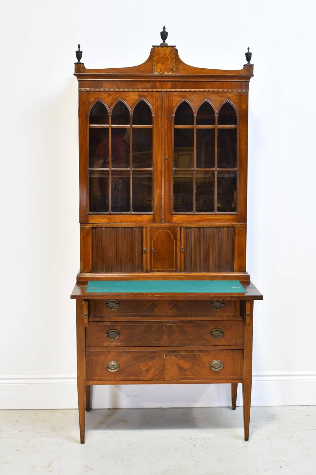 A very beautiful and exceptional Hepplewhite secretary bookcase from Massachusetts, probably Boston, from the Federal period, in mahogany with fine line inlays. The upper section has a stepped crest topped with urn finials and glazed doors with