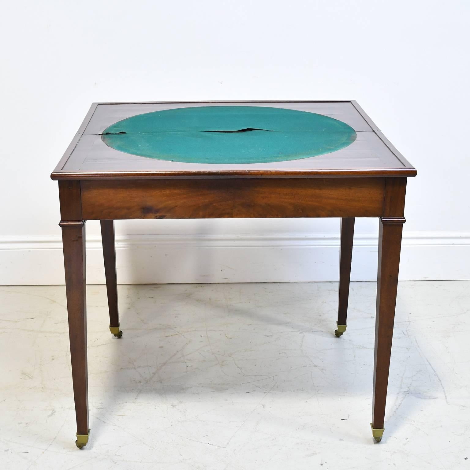 A very handsome games table in fine mahogany on tapered square legs with brass casters. Apron slides open to support hinged top with round inlaid baize, France, circa 1795.
Measures: 34