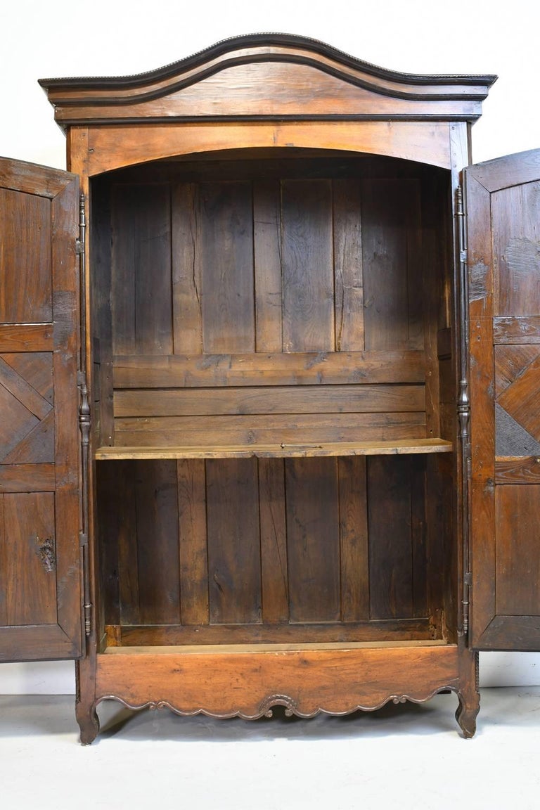 A lovely French armoire in walnut with arched bonnet, fluted astragal between the two paneled doors with parquetry decorating the middle panel of each, and resting on carved escargot feet. Offers one original interior shelf, original hardware and