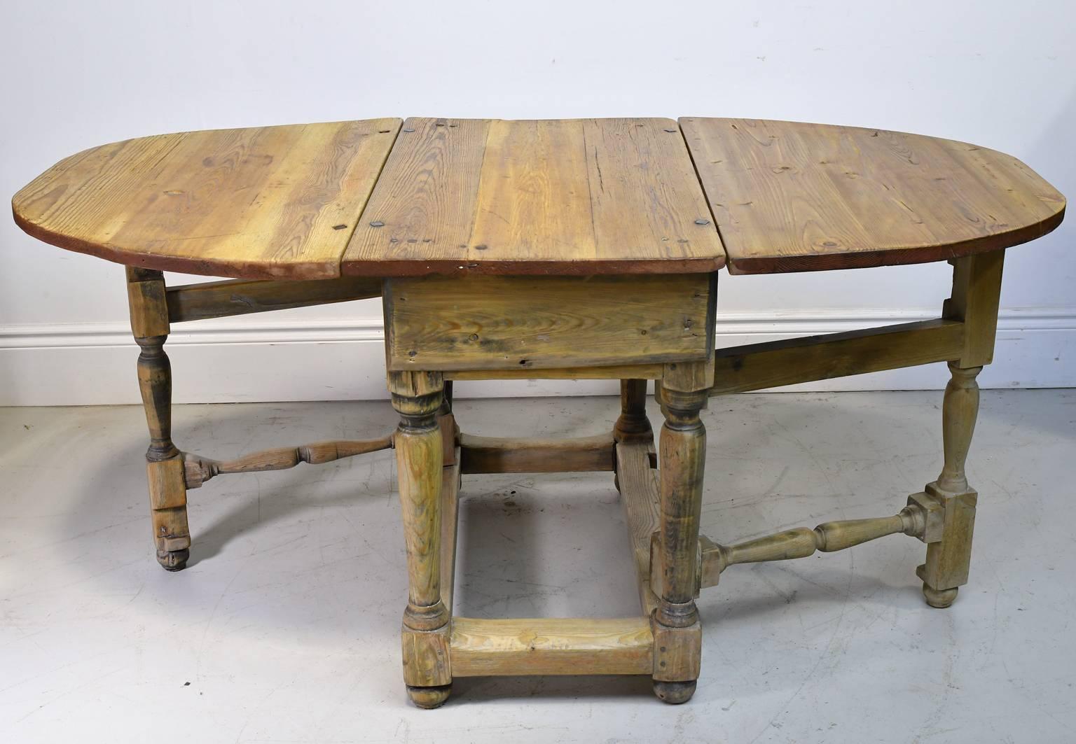 A large, rustic baroque farmhouse table with drop-leaves and gate-leg construction from Norway, circa 1740. The top is made of kiefer pine and the base is of white pine. A versatile table that is compact when closed, and expands into a larger table